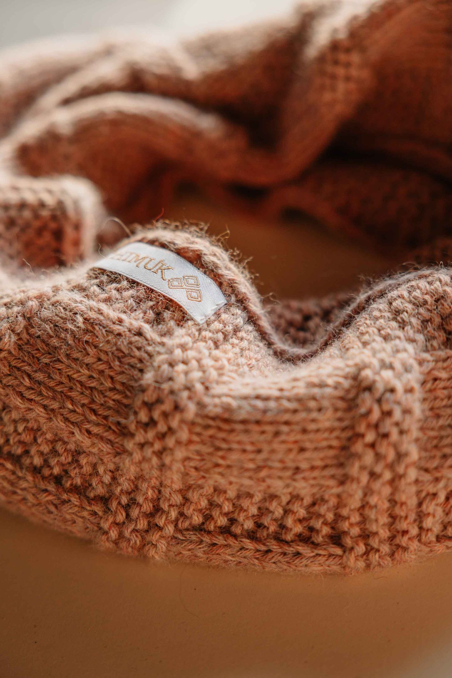 Close-up of a pink knitted wool hat with a small brand label inside the folded brim.