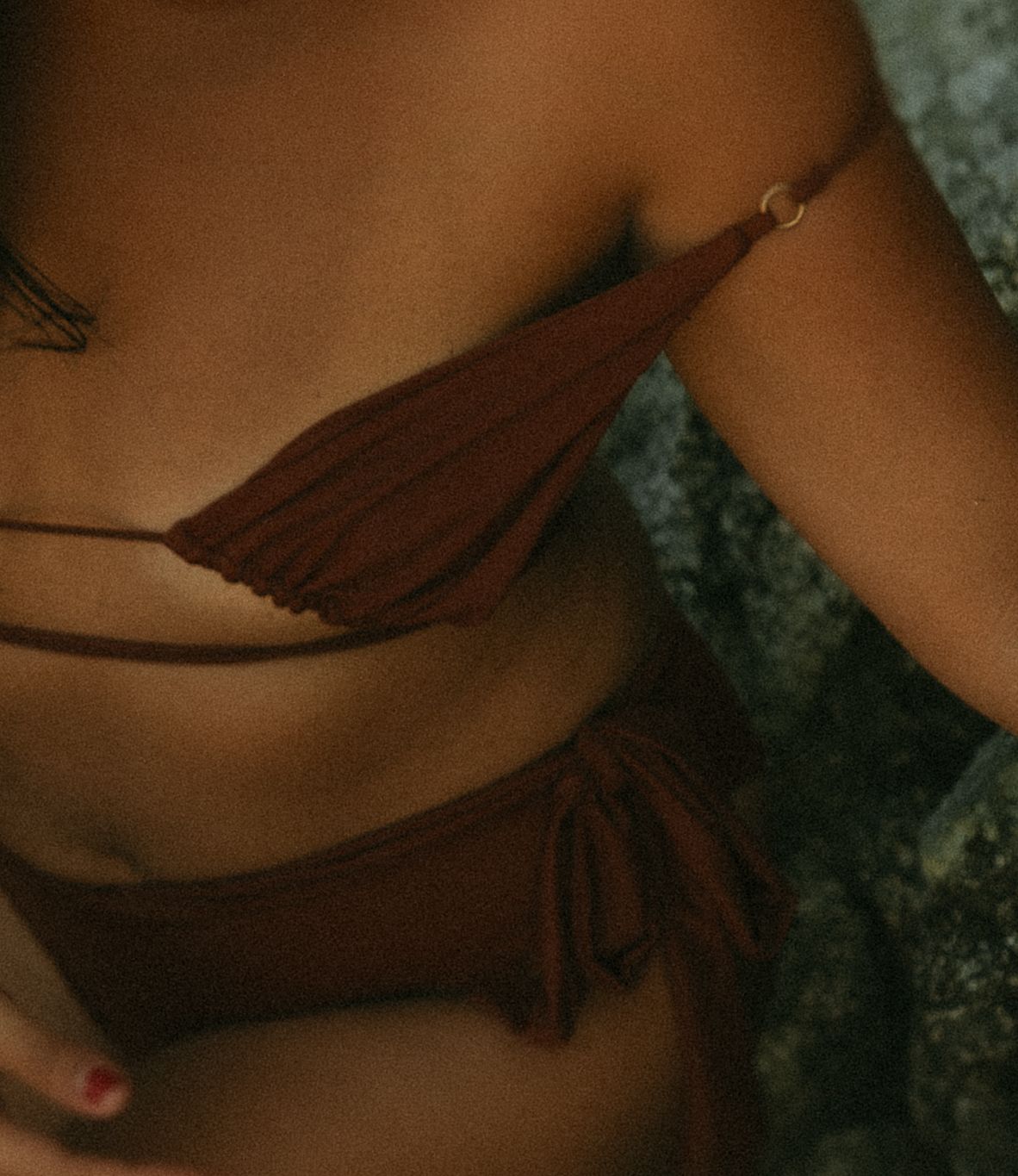 Brown fringe bikini top with tie-side bottoms in matching rust color, worn by a woman outdoors.