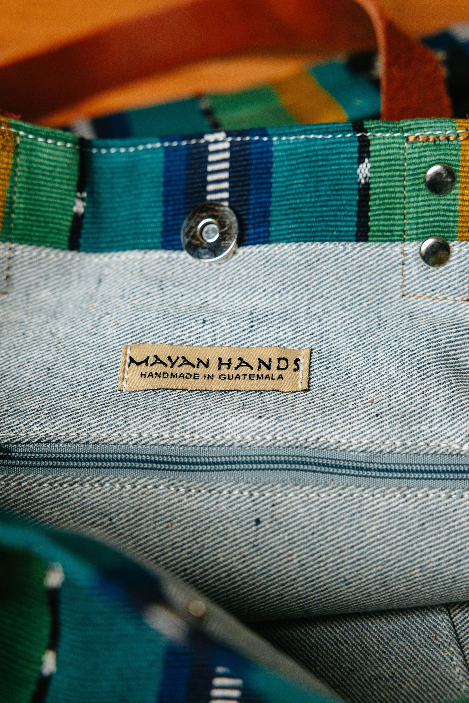 Mayan Hands handmade in Guatemala label inside a colorful striped tote bag with denim lining.
