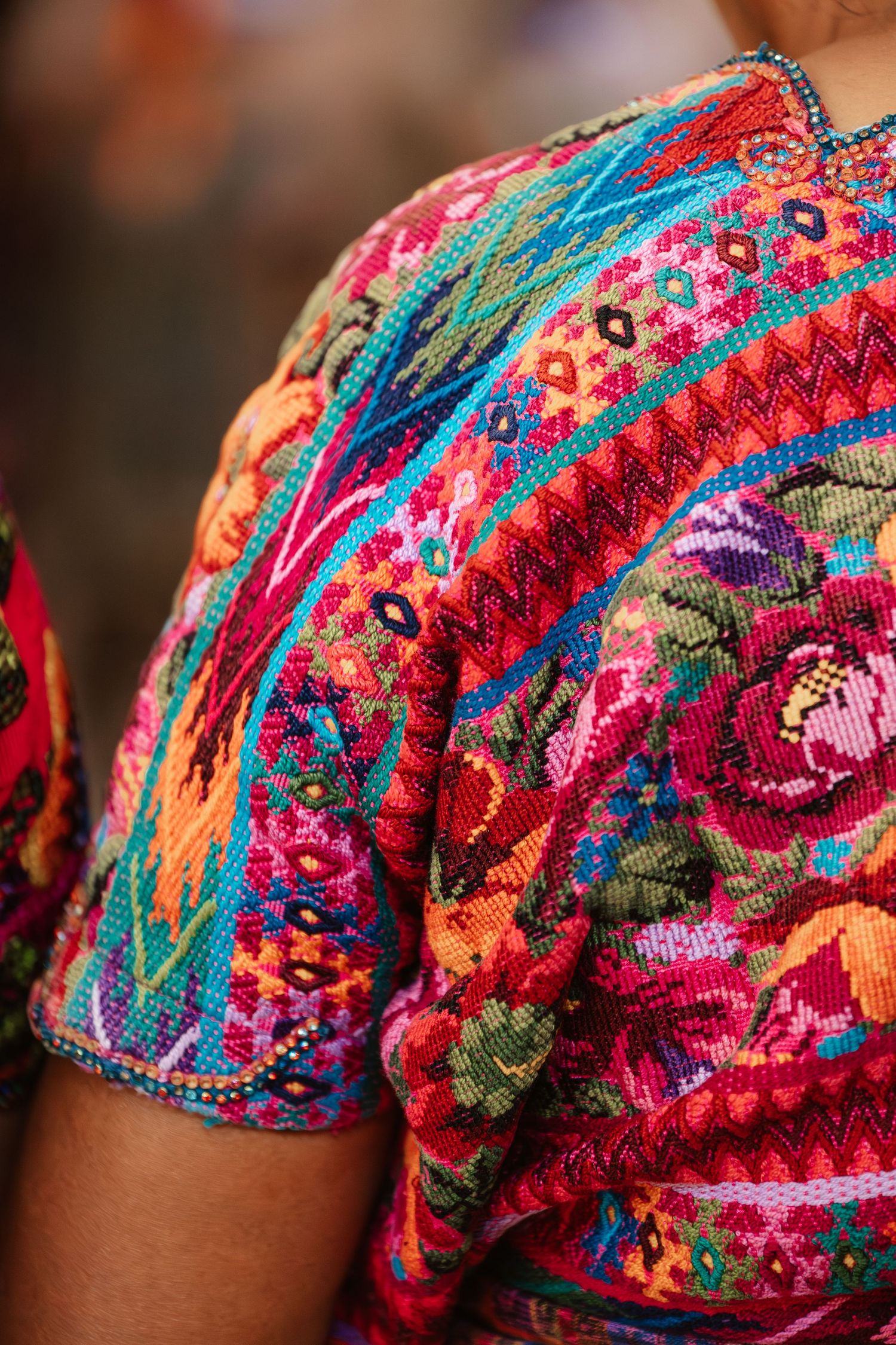 Vibrant Guatemalan huipil blouse with colorful traditional Mayan embroidery featuring floral and geometric patterns.