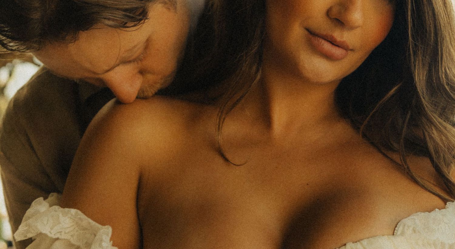 Two people sharing an intimate romantic moment in soft warm natural lighting.