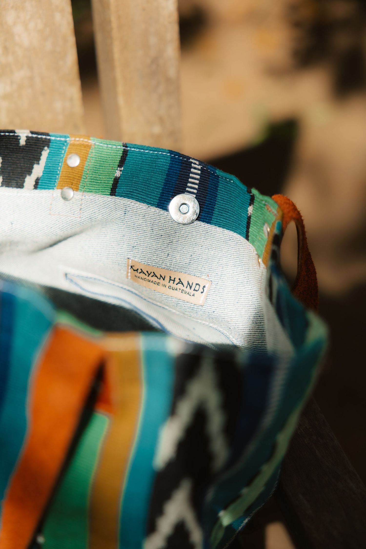 Close-up of a colorful Mayan Hands tote bag with ikat pattern fabric and snap closure, showcasing handcrafted textile detail.