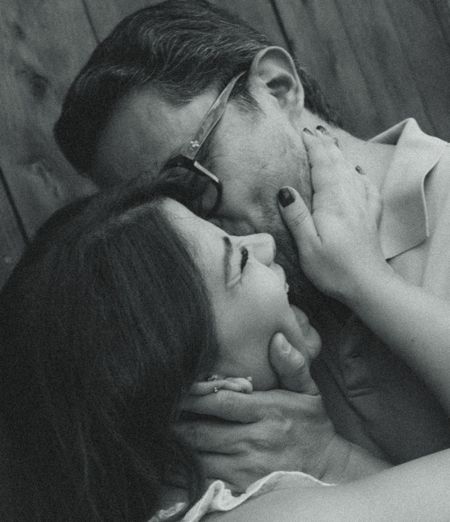 Black and white photo of a romantic couple sharing a tender kiss, man holding woman's face gently.