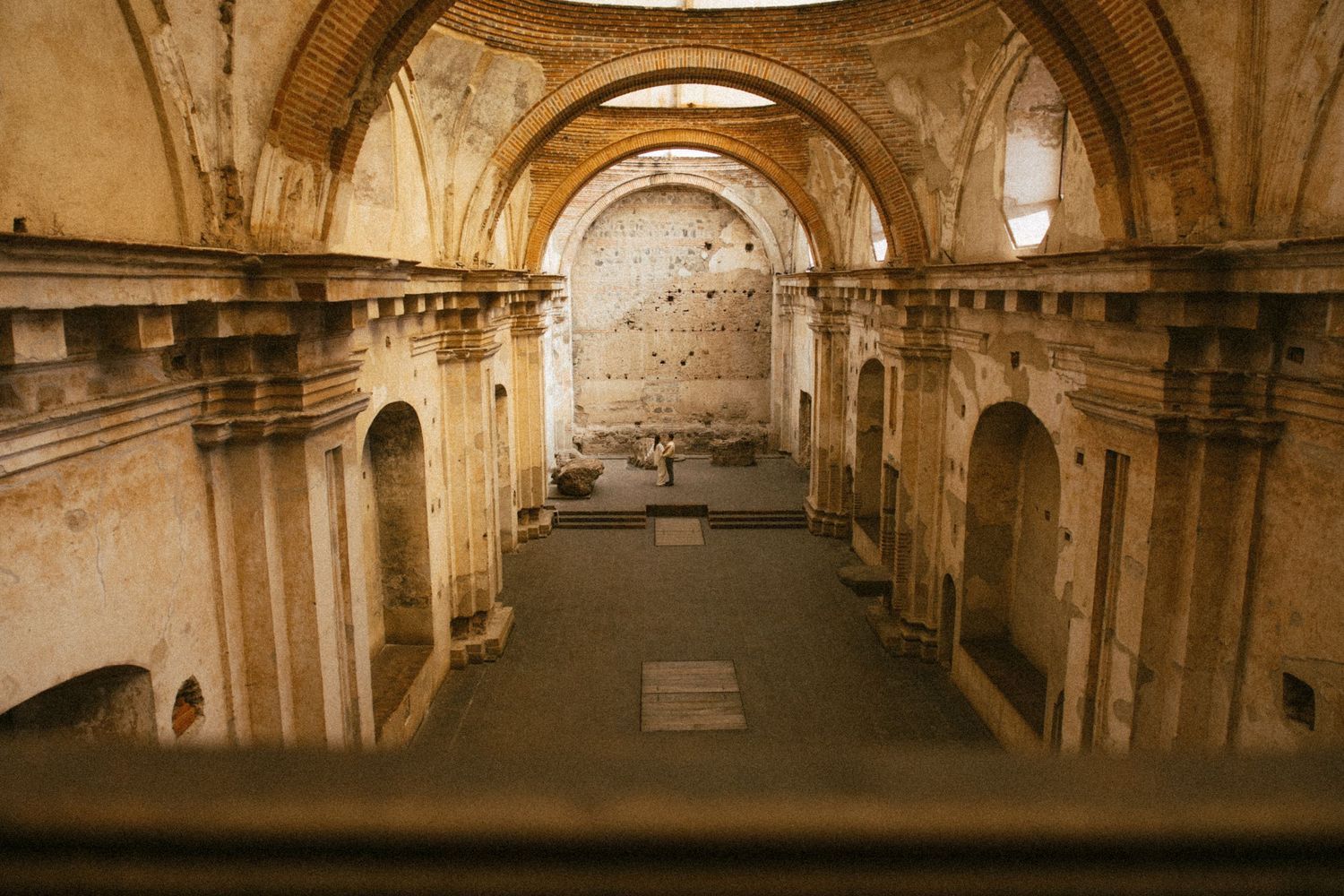 Interior view of an ancient ruined church with stone arches, weathered walls, and open nave in Antigua, Guatemala.