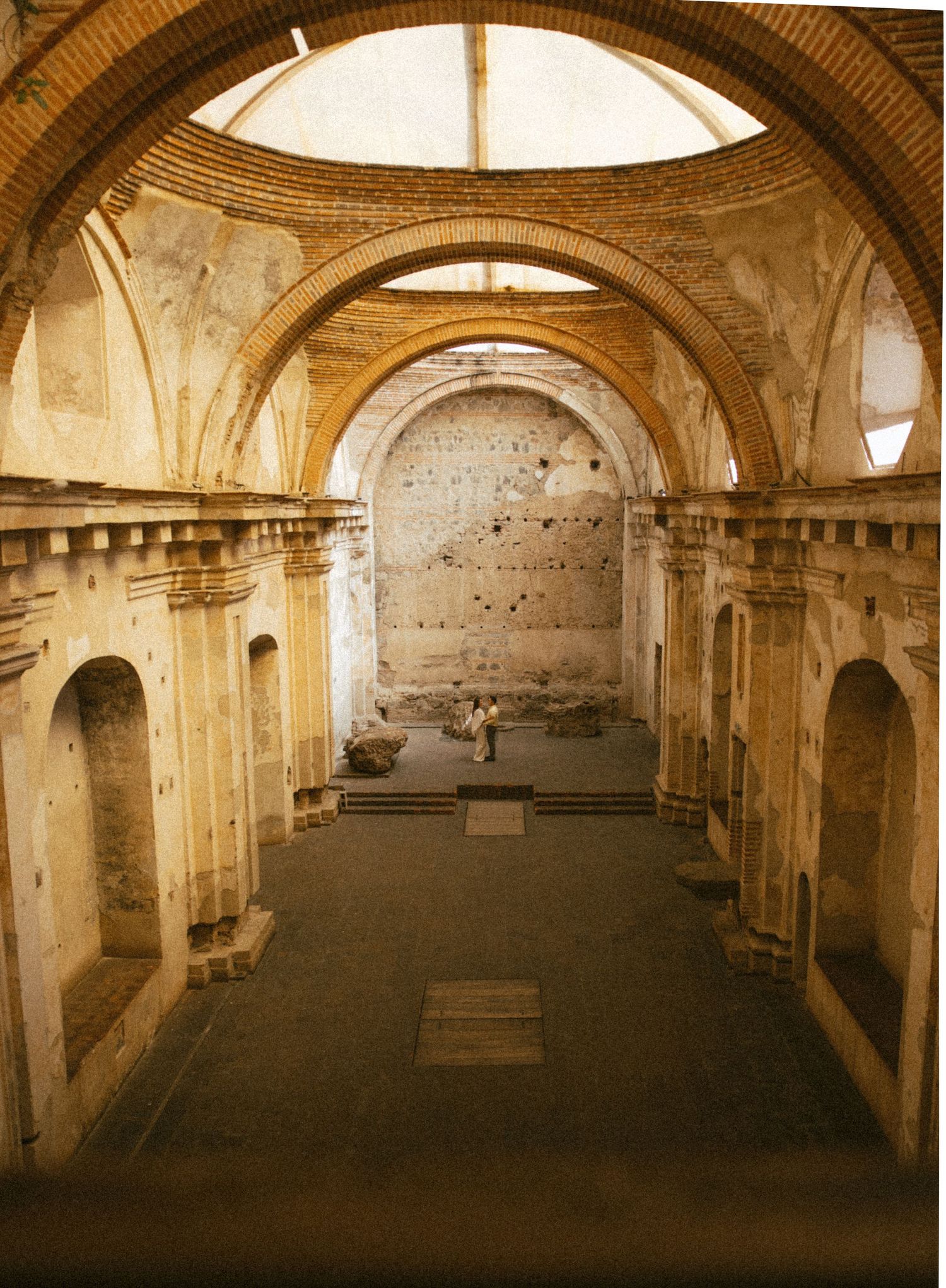 Interior of a ruined historic church with arched ceilings, stone walls, and natural light streaming through an open dome.