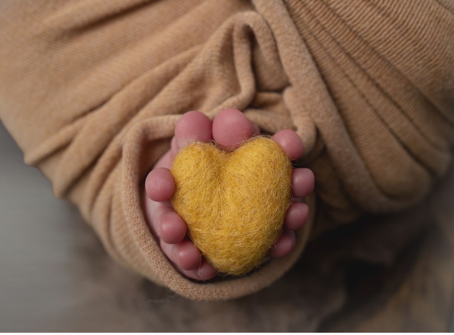 Newborn toes curled around a yellow felt heart during a styled studio newborn session in Austin