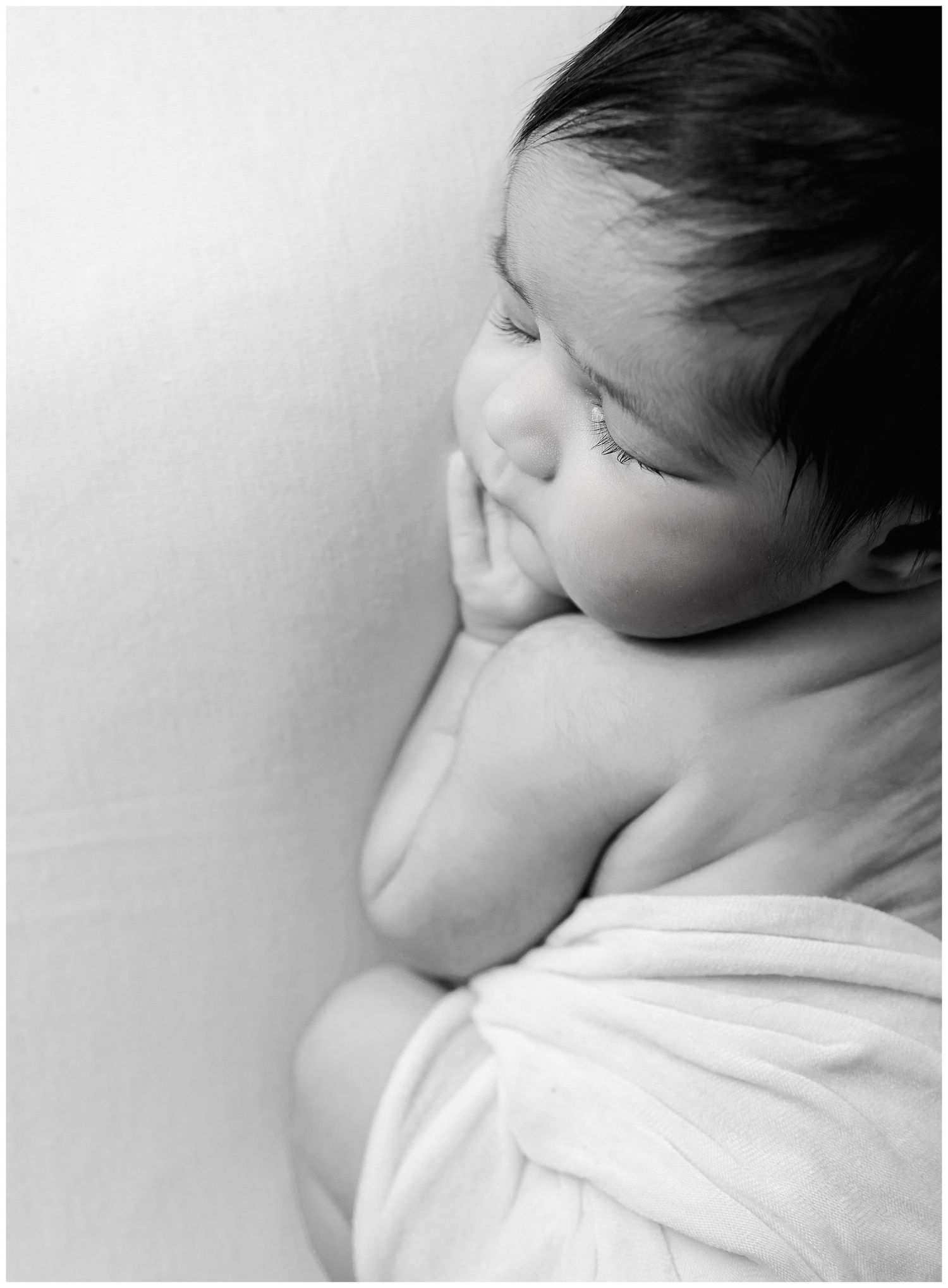 Black and white close up portrait of a newborn baby posed safely on a soft backdrop at Austin Newborn Photography studio.