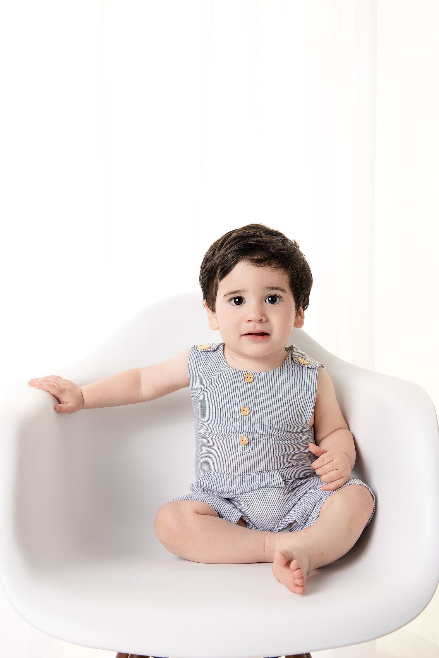 Milestone portrait in austin texas, 6 month old boy sitting in modern white chair with withe background and vintage romper.