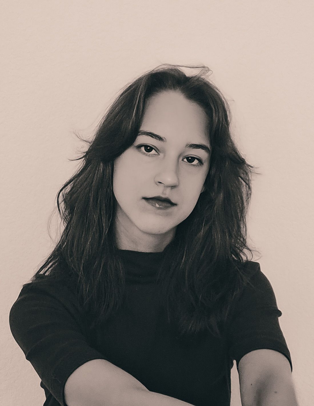 Black and white portrait of a young woman with dark hair wearing a black t-shirt against a light background.