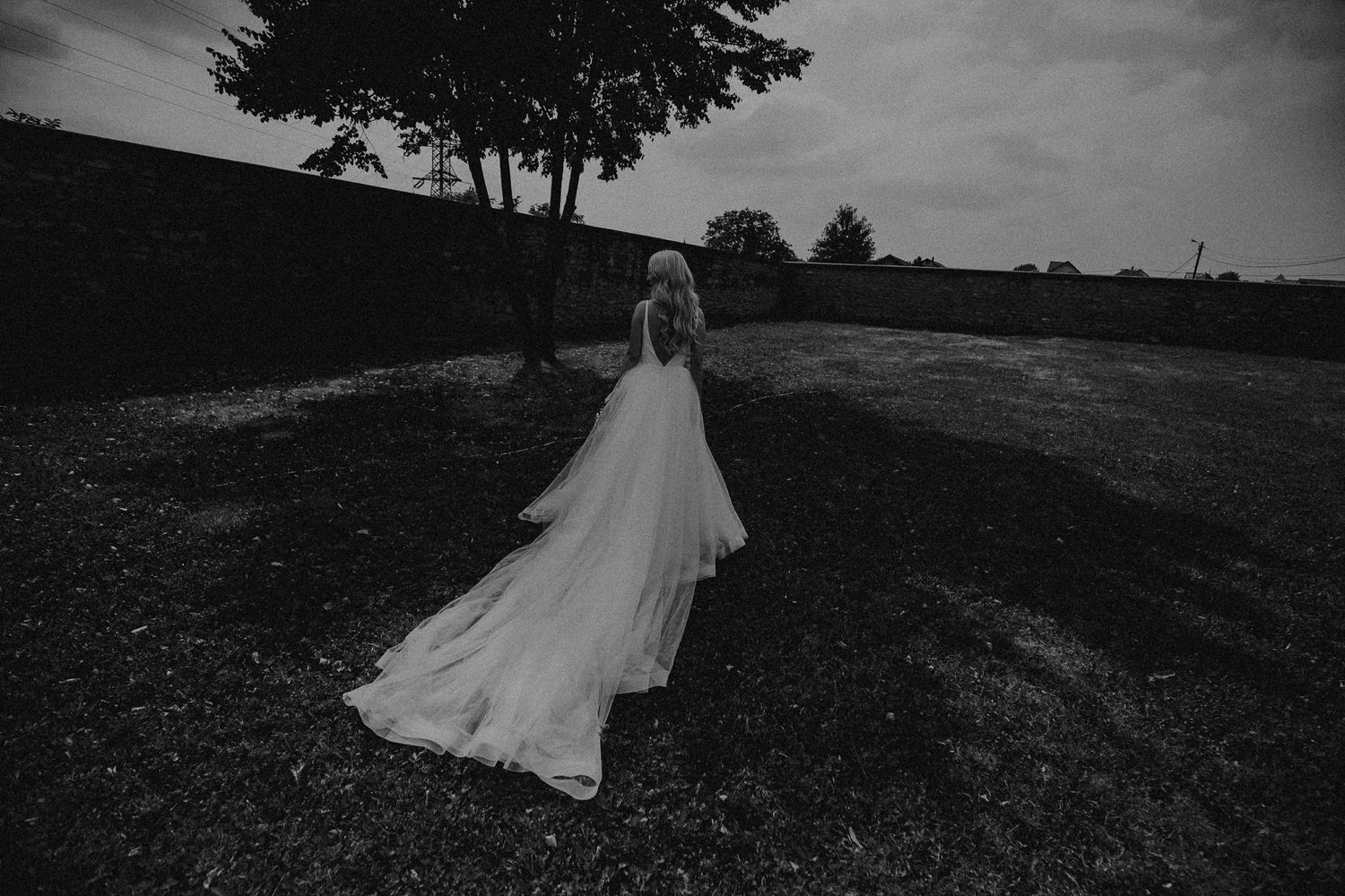 Black and white photo of bride in flowing tulle gown walking outdoors.
