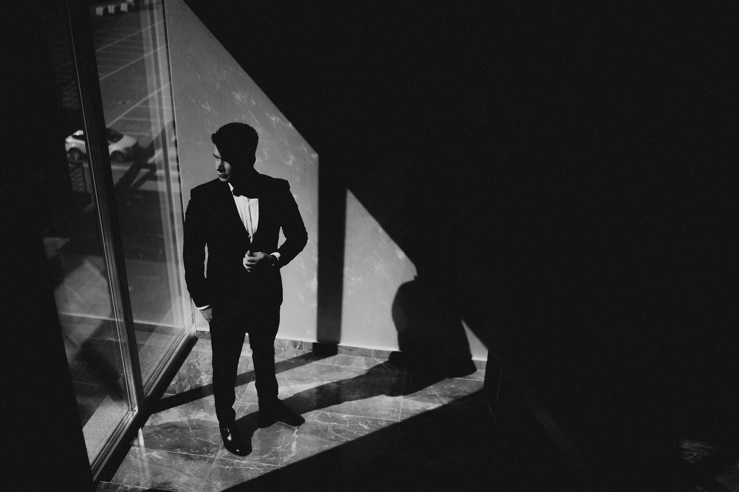 Elegant silhouette of a man in a tuxedo standing in dramatic light and shadow.