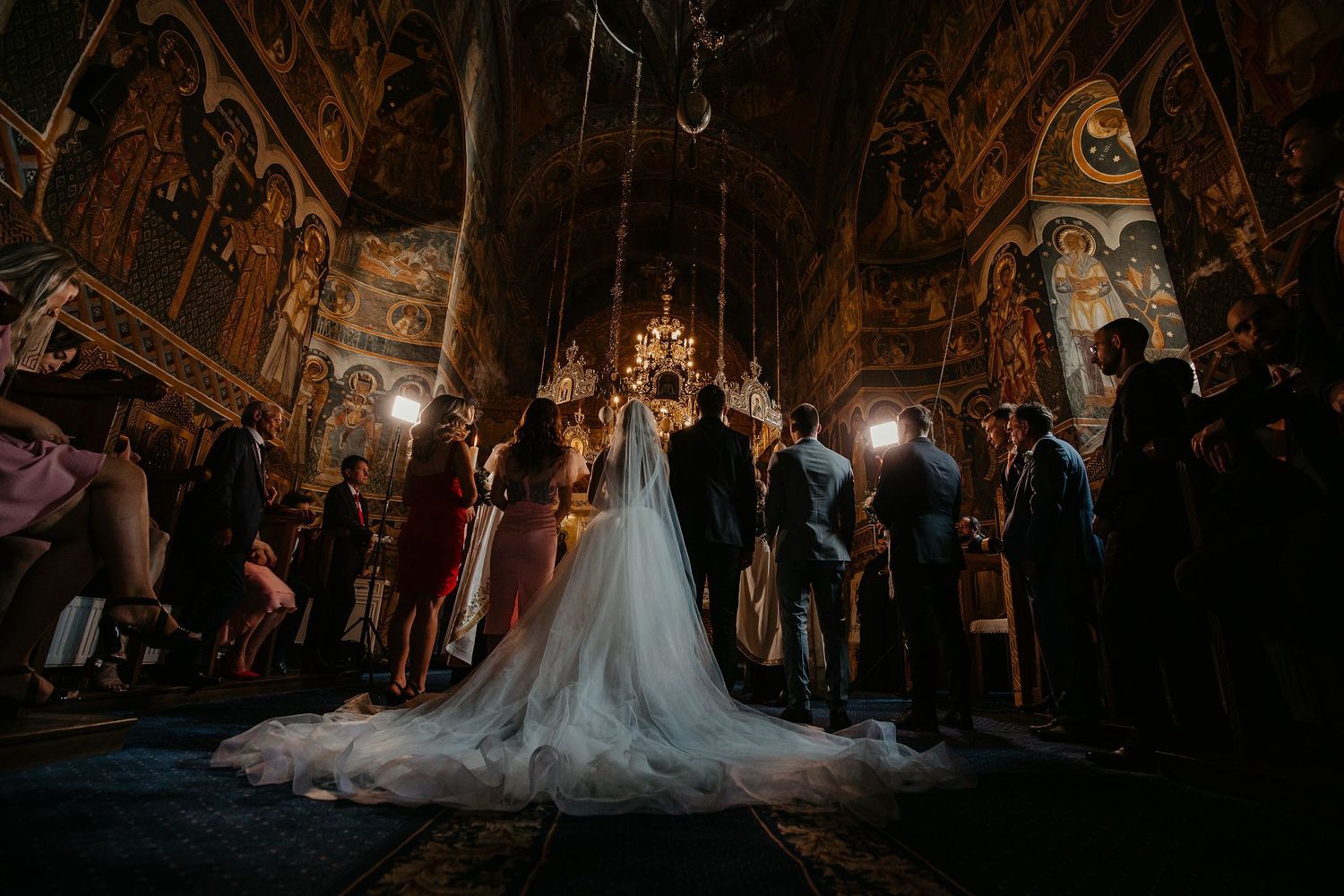 Bride and groom stand before the altar in a beautifully decorated Orthodox church during their wedding ceremony.