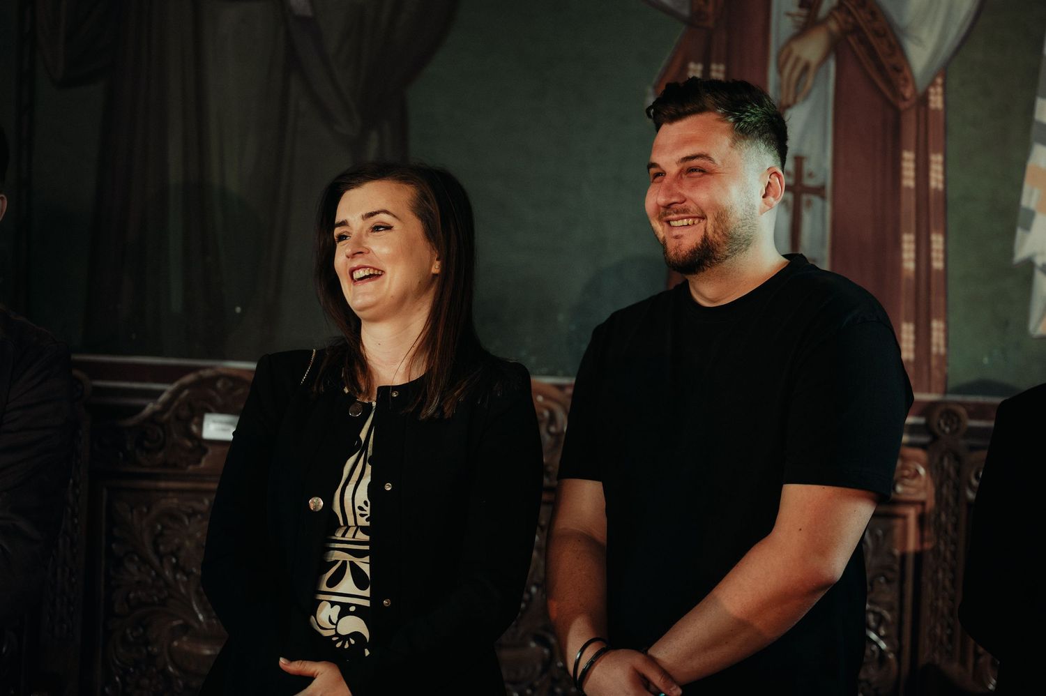 Young couple smiling and laughing together during a baptism celebration inside a church.