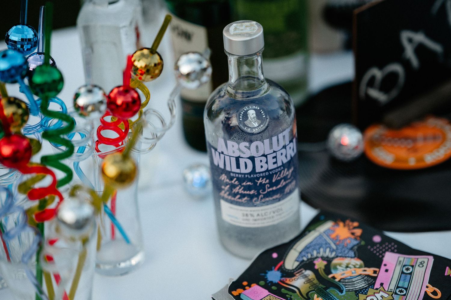 Absolut Wild Berri vodka bottle surrounded by colorful party streamers and decorations on a table.