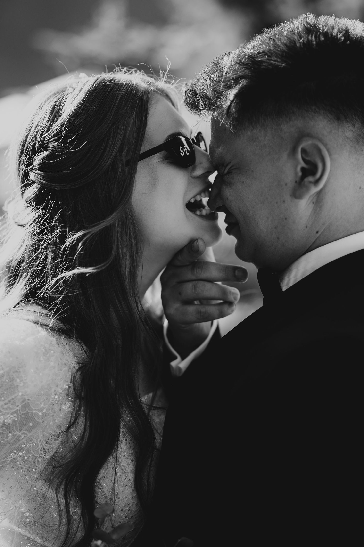 Black and white close-up of laughing bride and groom touching foreheads at their wedding.