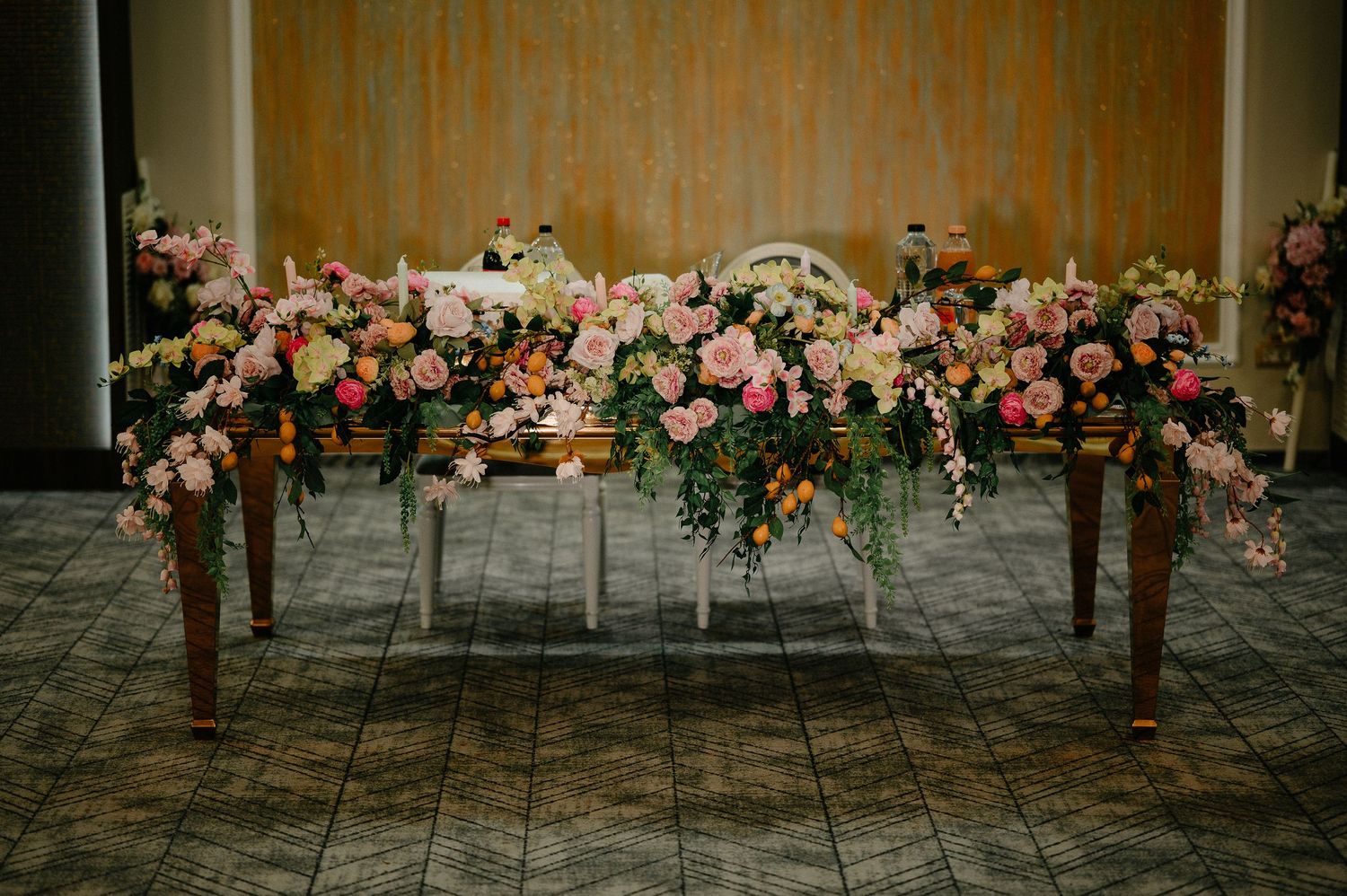 Elegant wedding sweetheart table adorned with lush pink and peach floral arrangements and candles.