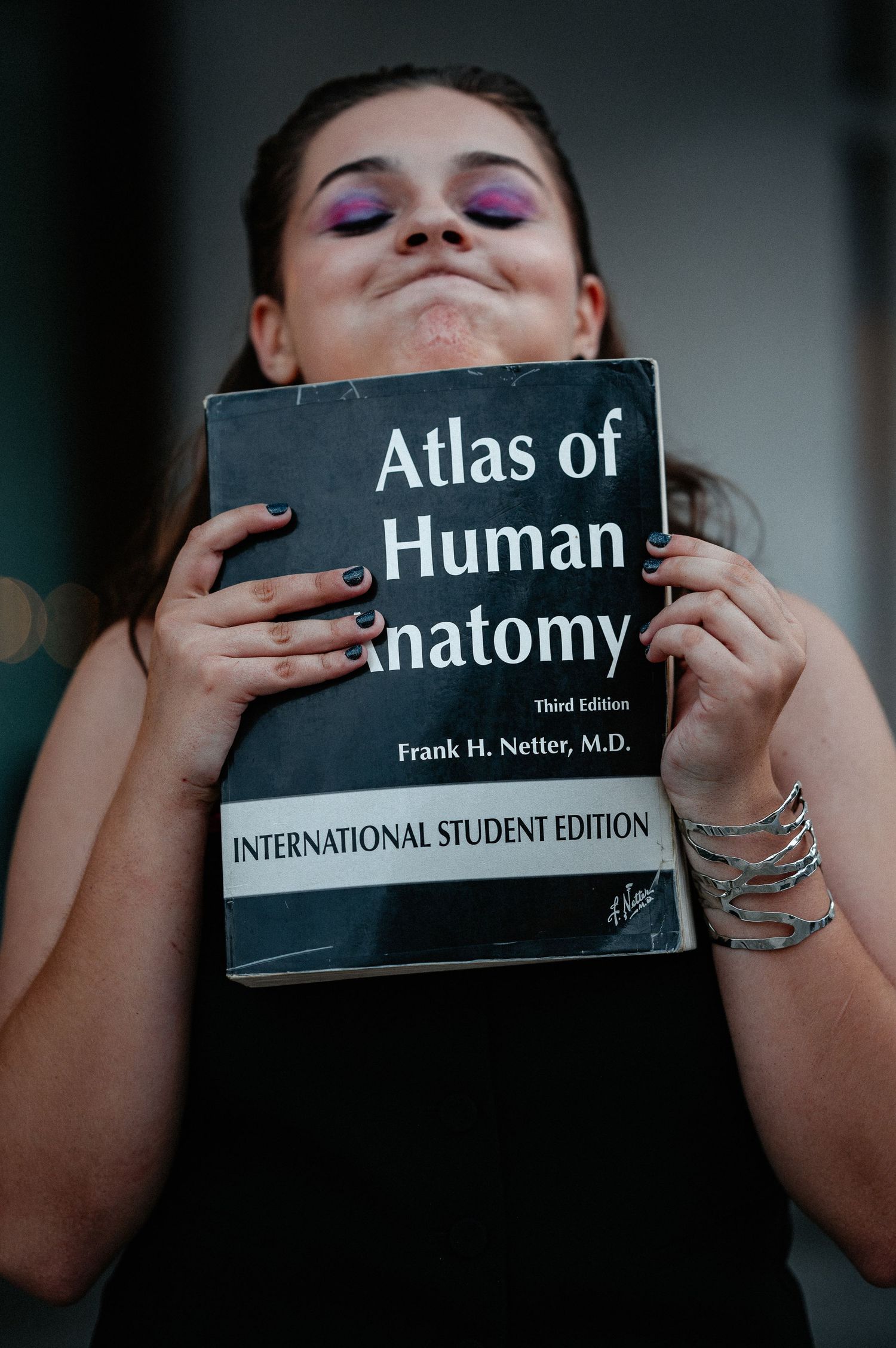 Young woman holding Atlas of Human Anatomy textbook by Frank H. Netter MD.