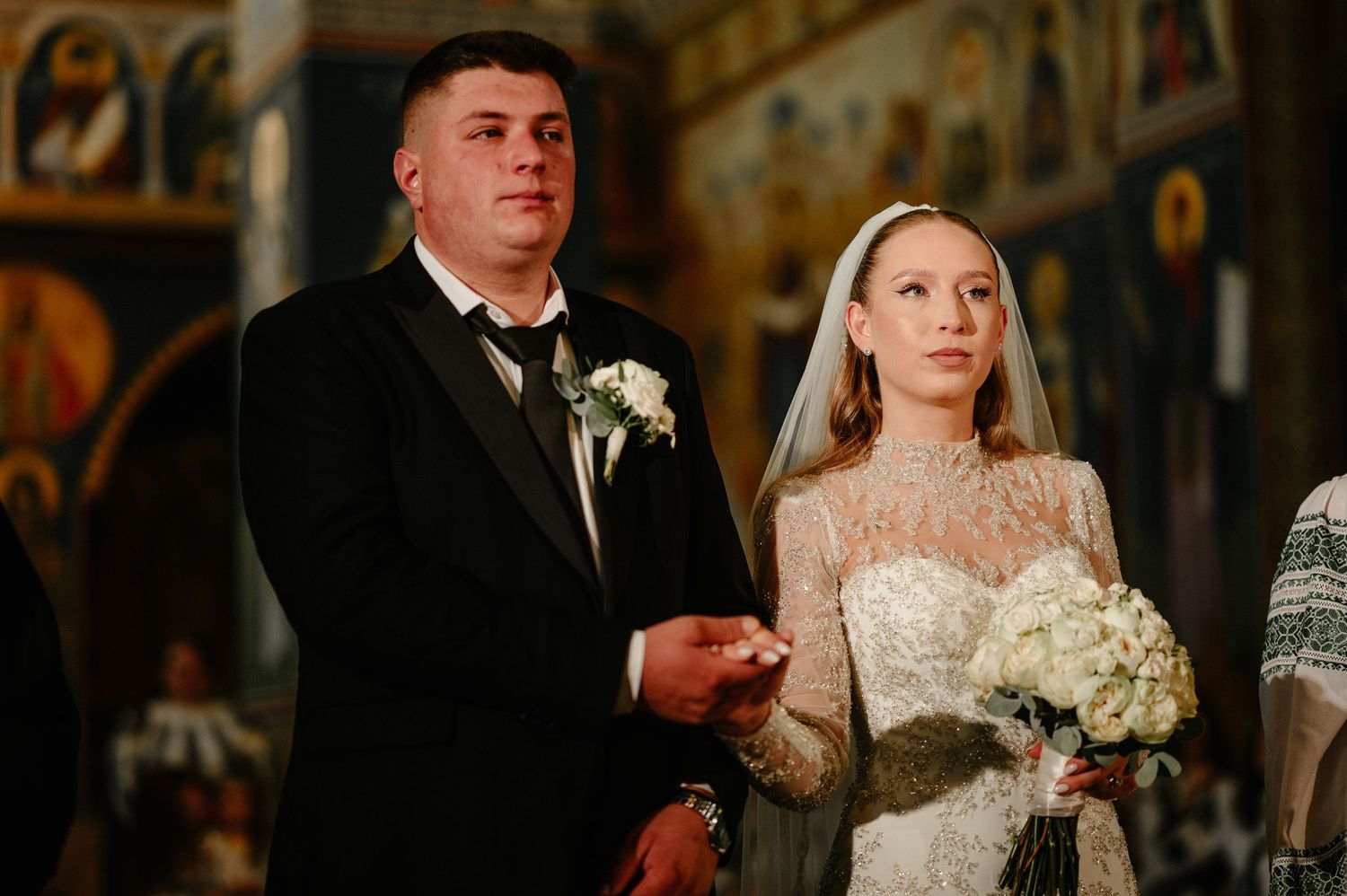 Bride and groom exchange vows inside an ornate Orthodox church during their wedding ceremony.