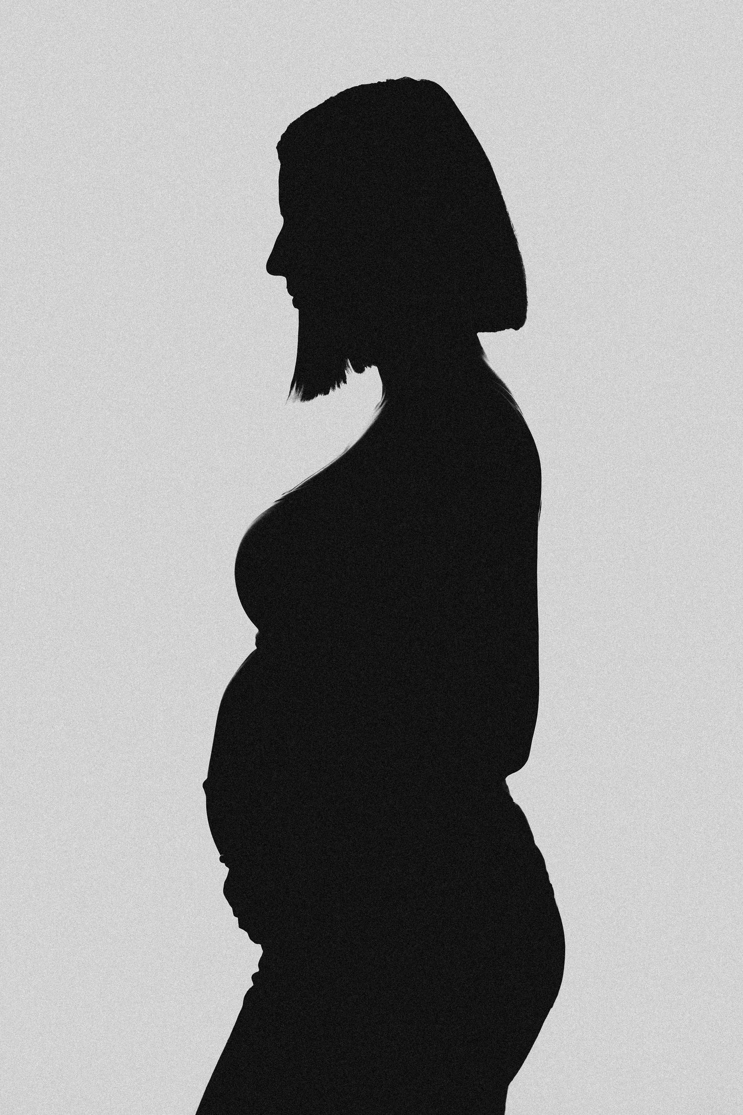 Black and white silhouette of a pregnant woman with short hair standing in profile view.