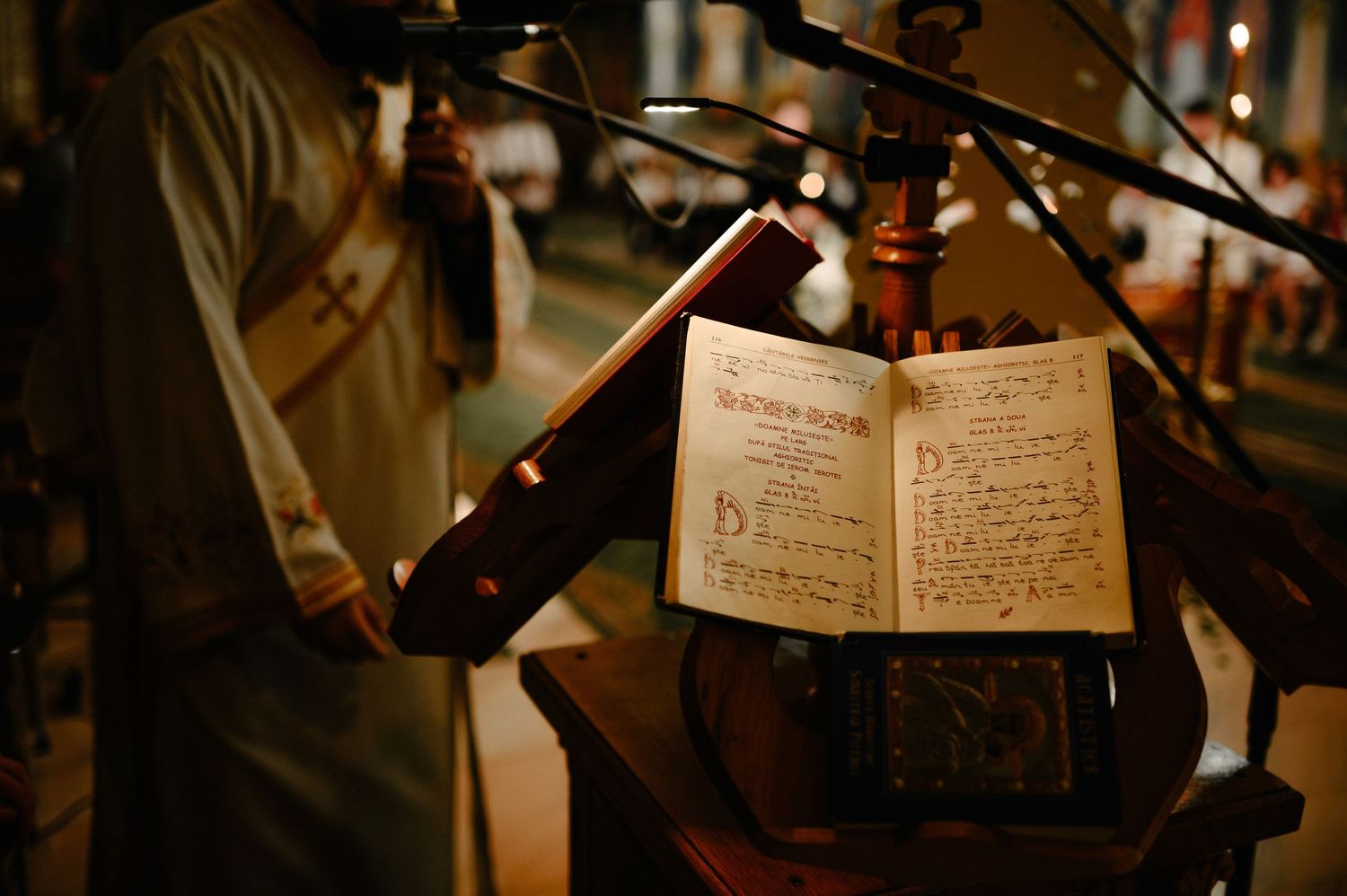 Ancient illuminated manuscript on wooden lectern during traditional church ceremony with choir.