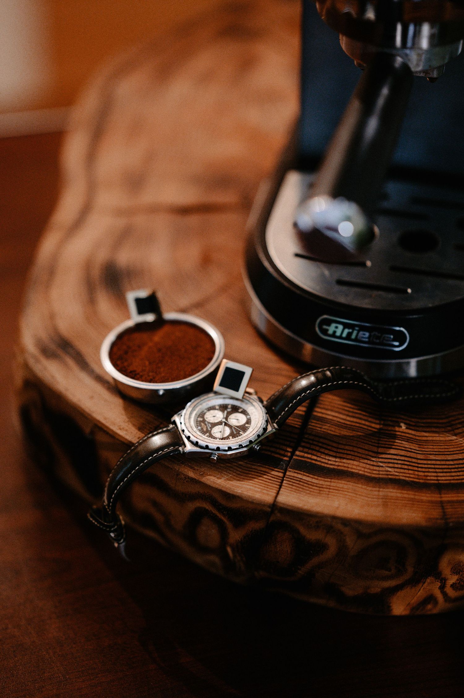 Groom's accessories including a Breitling chronograph watch and cufflinks beside an espresso machine.