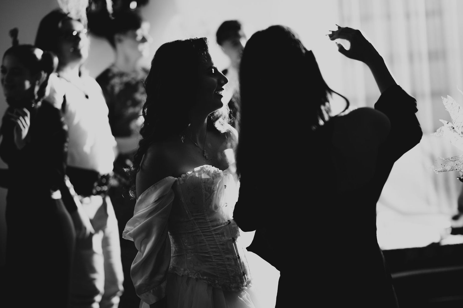 Black and white photo of people dancing at a Halloween party, with a woman in a white corset.