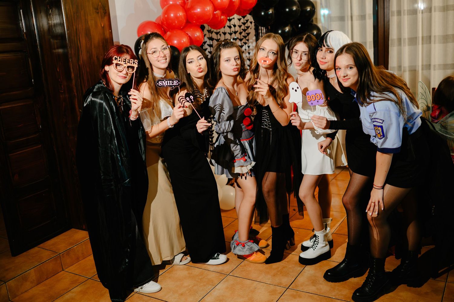 Group of eight young women posing with fun props and costumes at a birthday party celebration.
