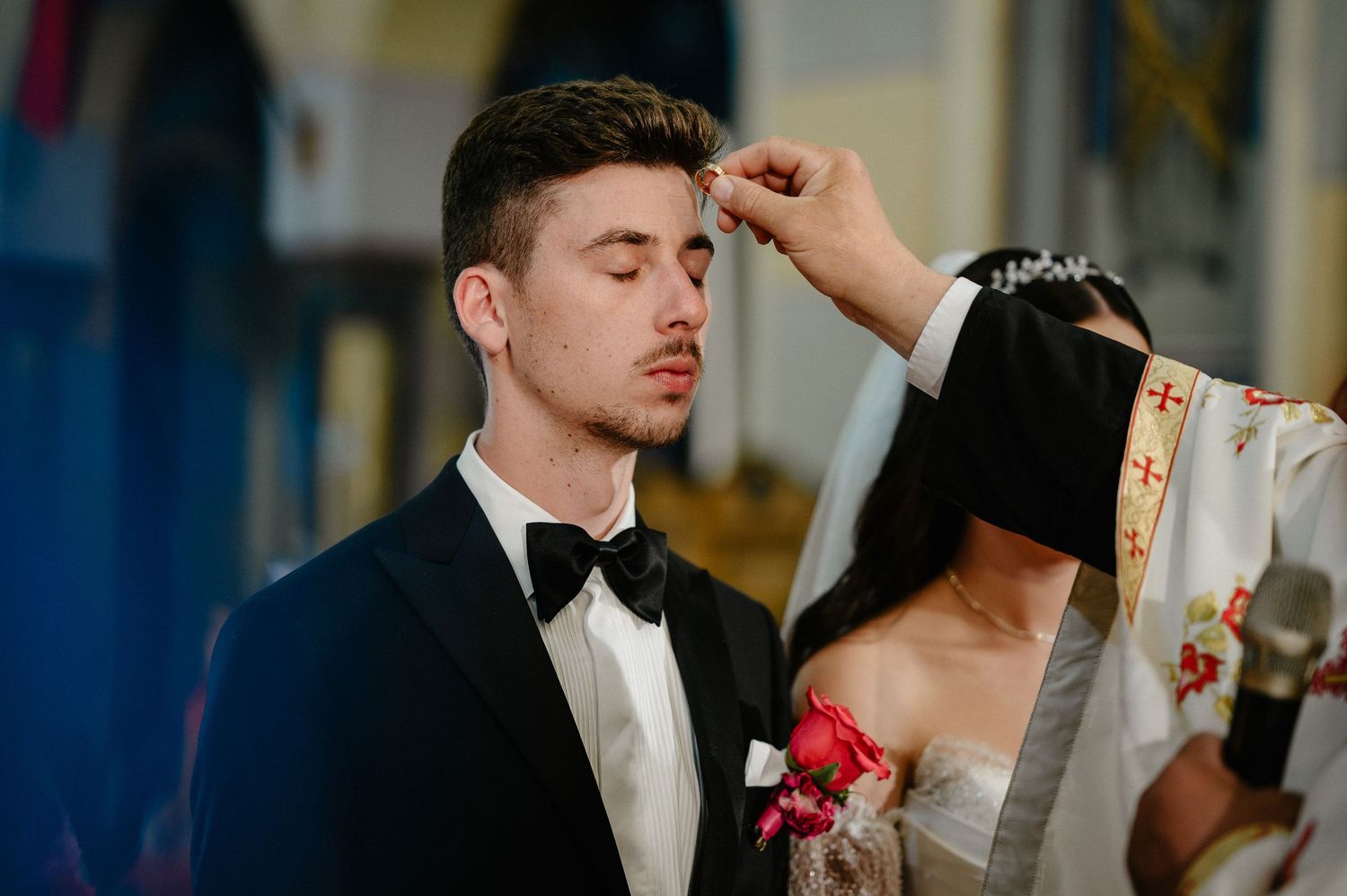 Orthodox priest anointing the groom during a traditional church wedding ceremony.
