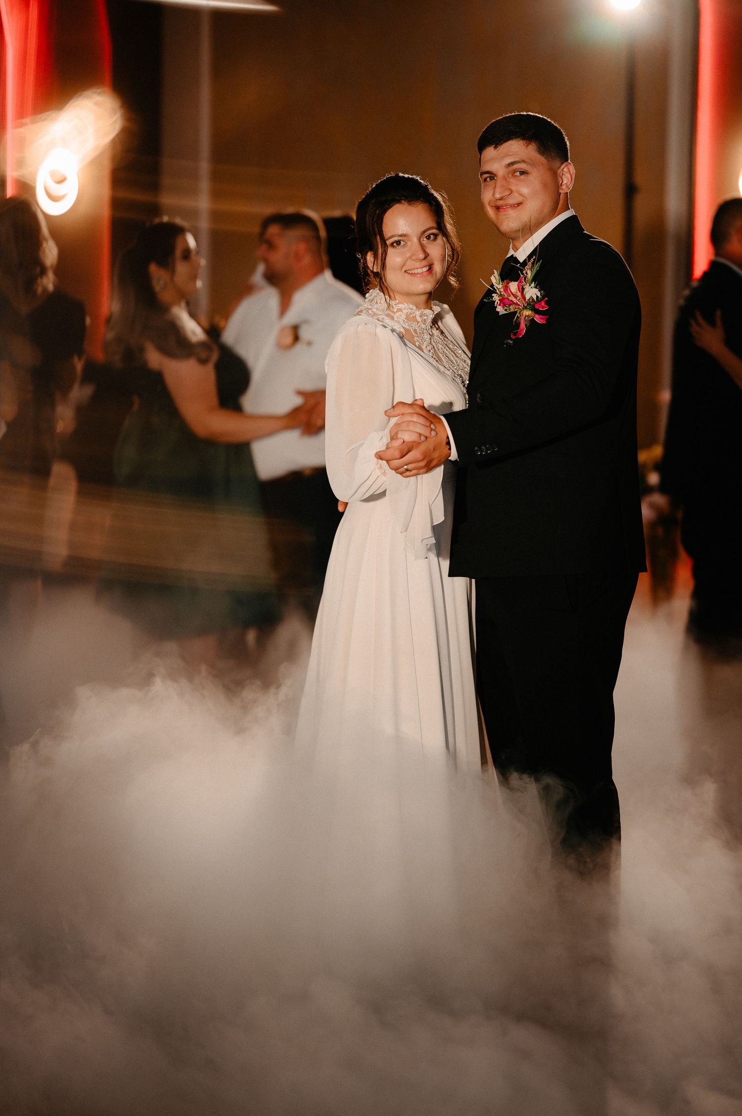 Newlyweds sharing first dance surrounded by dramatic fog on dance floor.