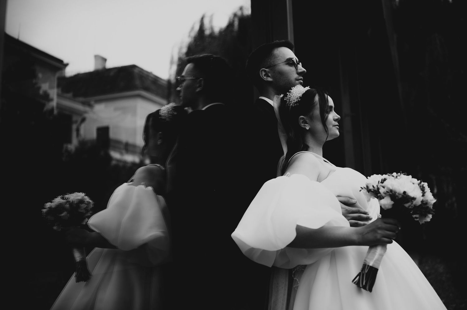 Black and white wedding photo of bride and groom embracing outdoors, bride holding bouquet.