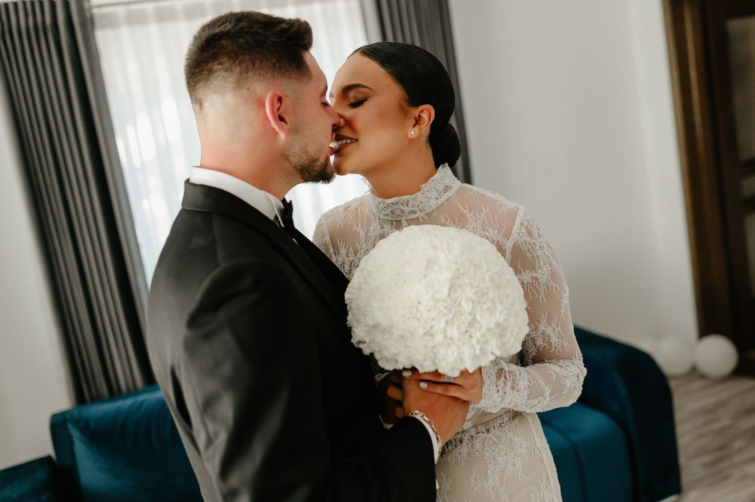 Bride and groom sharing a romantic kiss holding white hydrangea bouquet before wedding.