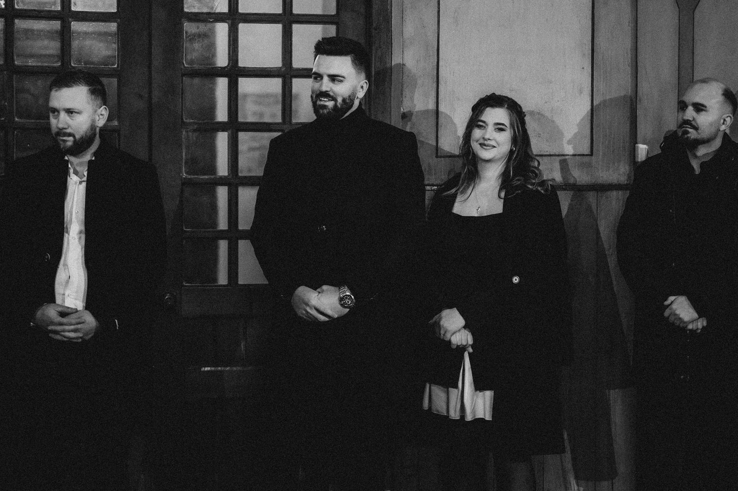 Black and white photo of four adults standing outside church after baptism celebration.