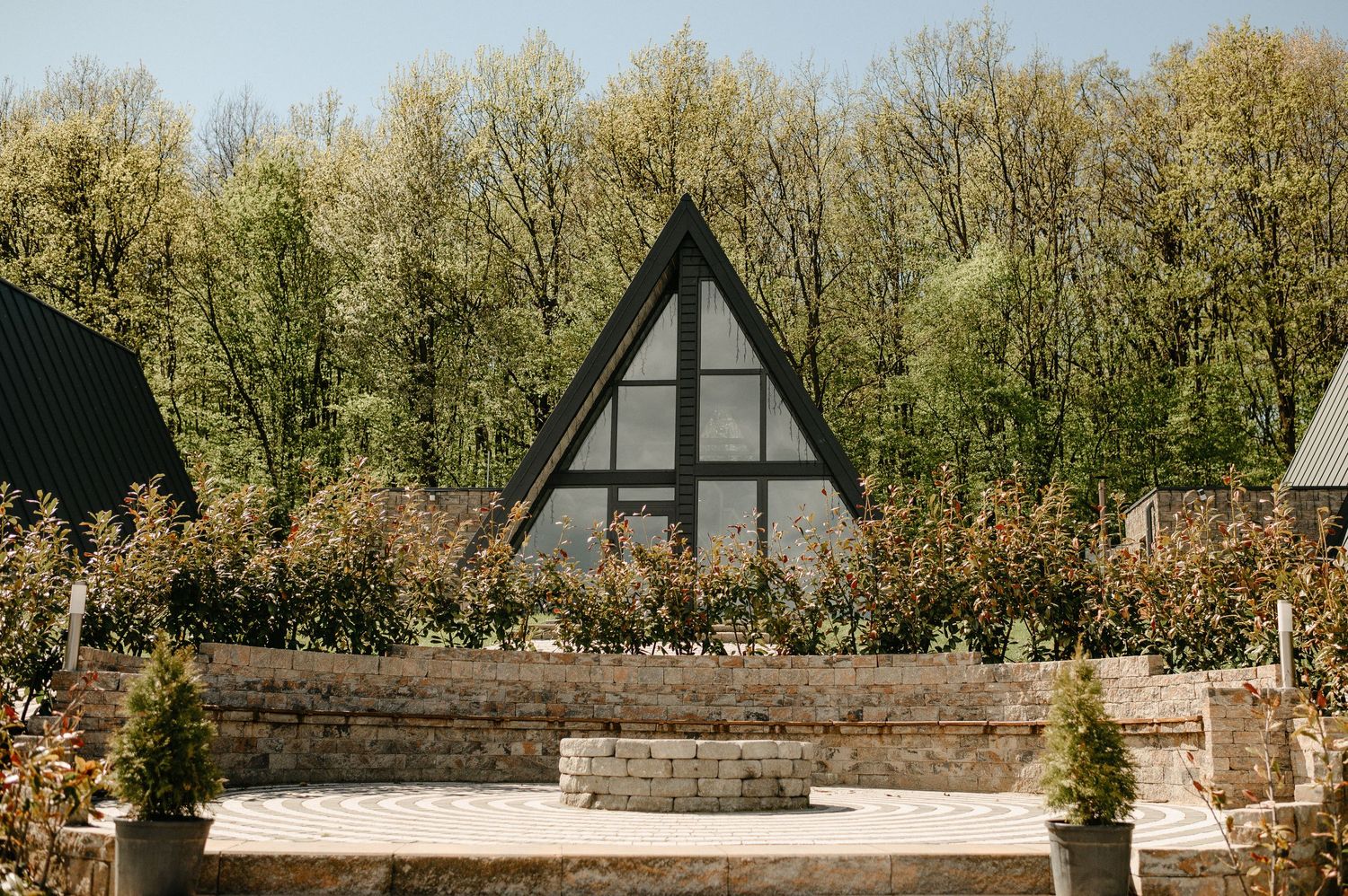 A-frame cabin with large triangular window surrounded by lush spring trees.