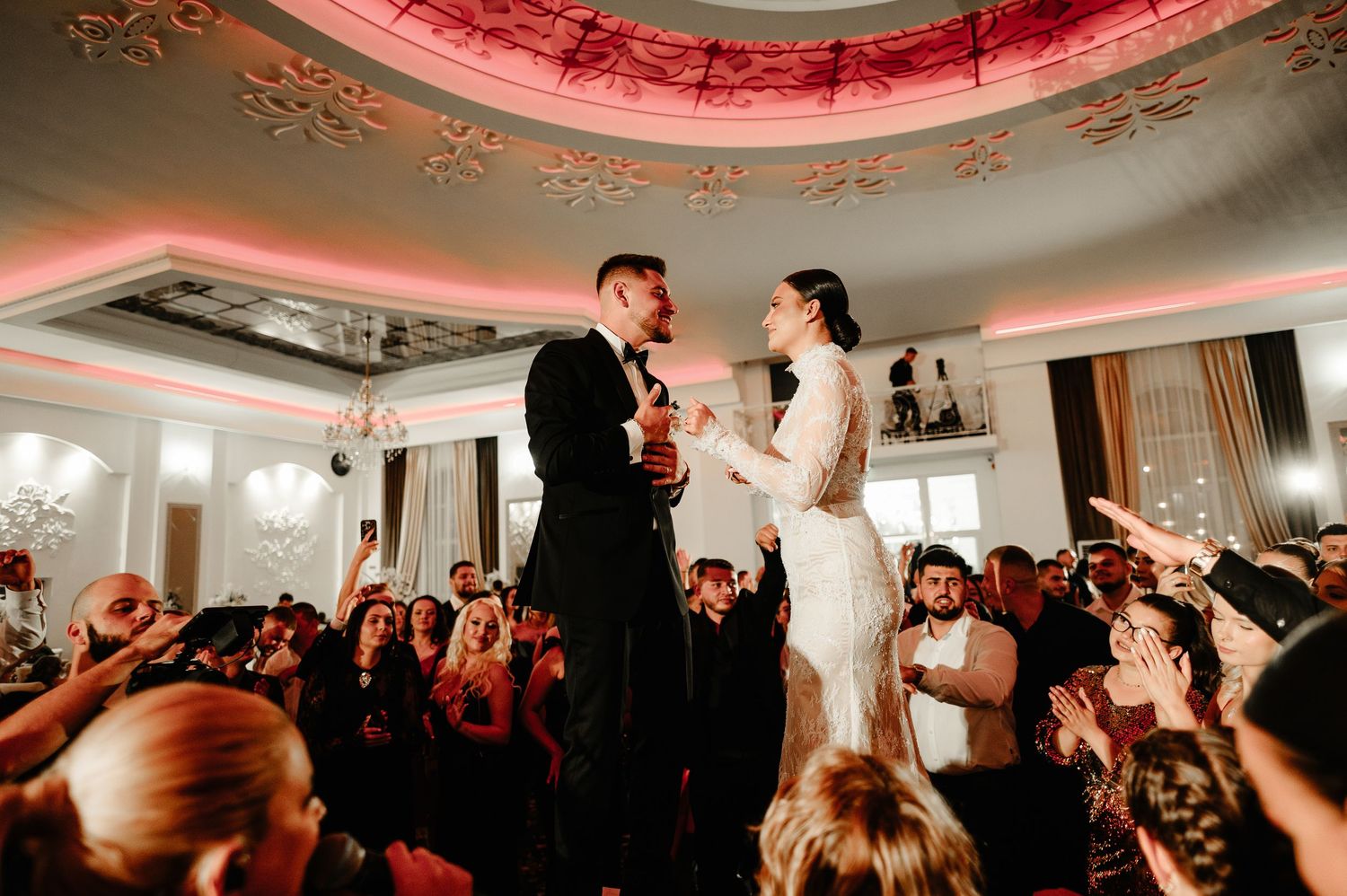 Newlyweds sharing a romantic moment on the dance floor surrounded by celebrating wedding guests.
