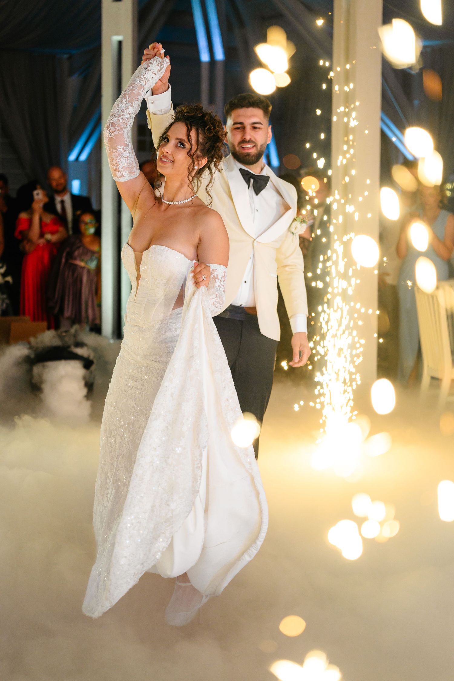 Bride and groom share first dance surrounded by sparkling lights and fog at elegant wedding reception.