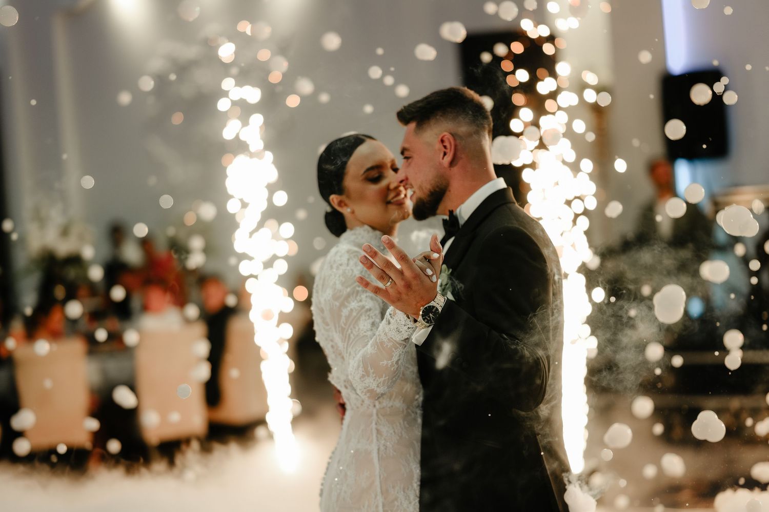 Bride and groom sharing romantic moment surrounded by sparkling fireworks at wedding reception.