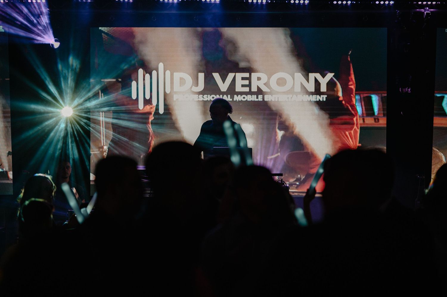 DJ Verony professional mobile entertainment performing on stage with silhouetted crowd at a wedding event.