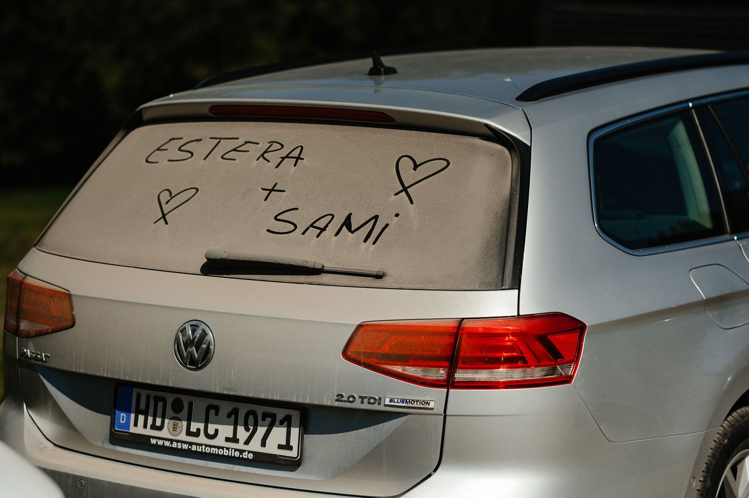 Car rear window with Estera and Sami written in dust with hearts for a wedding.