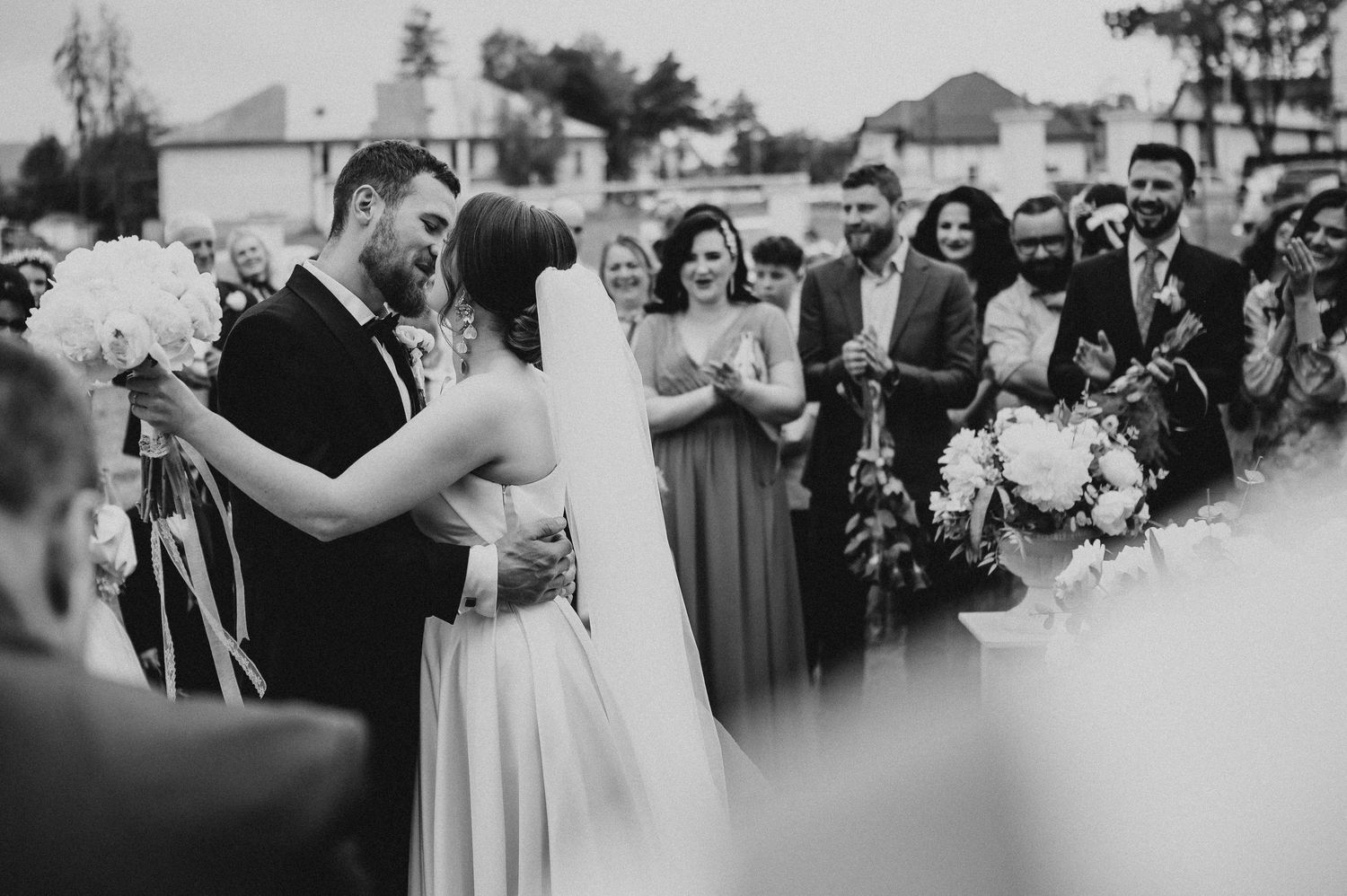 Emotional black and white photo of bride and groom sharing first kiss at wedding ceremony.