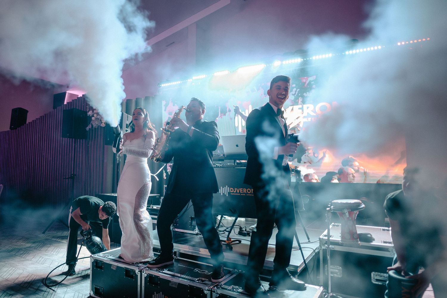 Live band performance on stage with colorful smoke effects and dramatic lighting at a wedding reception.