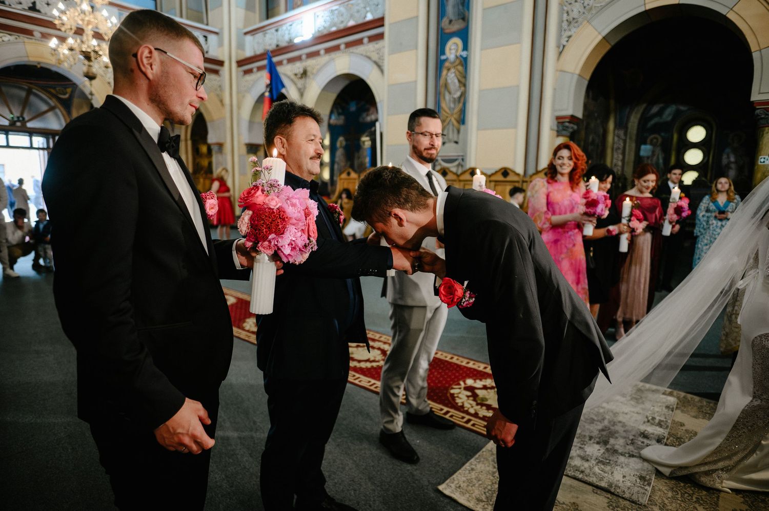 Groomsmen in tuxedos share a joyful moment with a child during a church wedding ceremony.