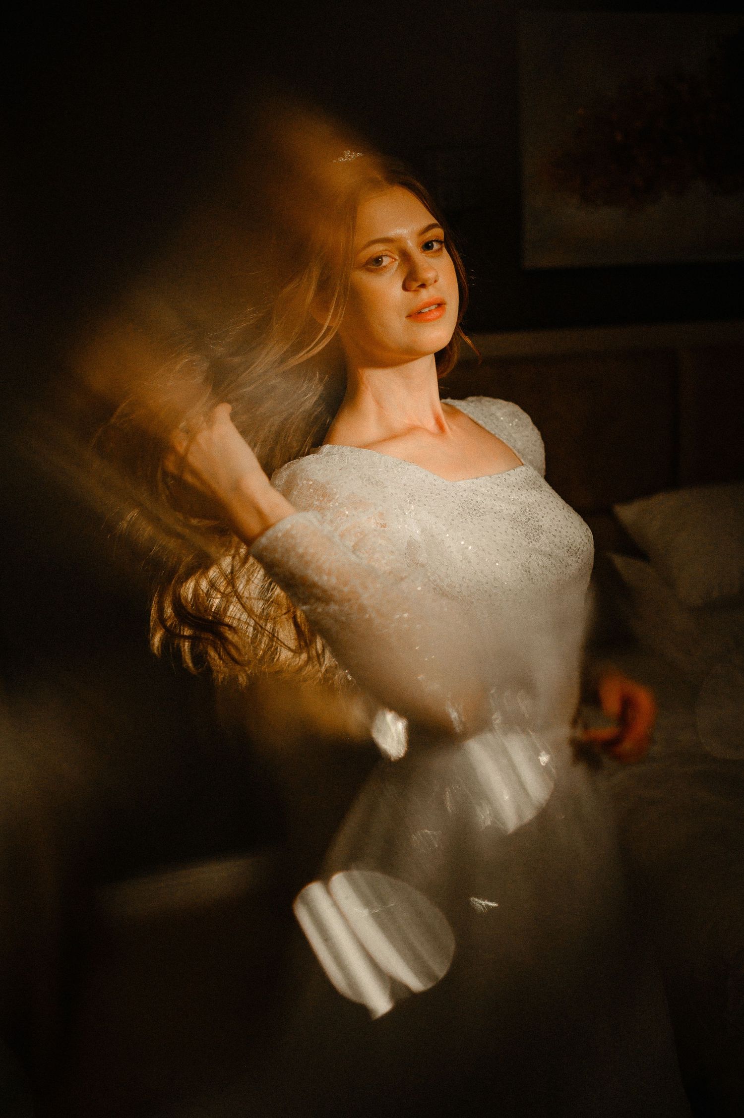 Bride in white lace wedding dress captured with artistic motion blur in warm light.