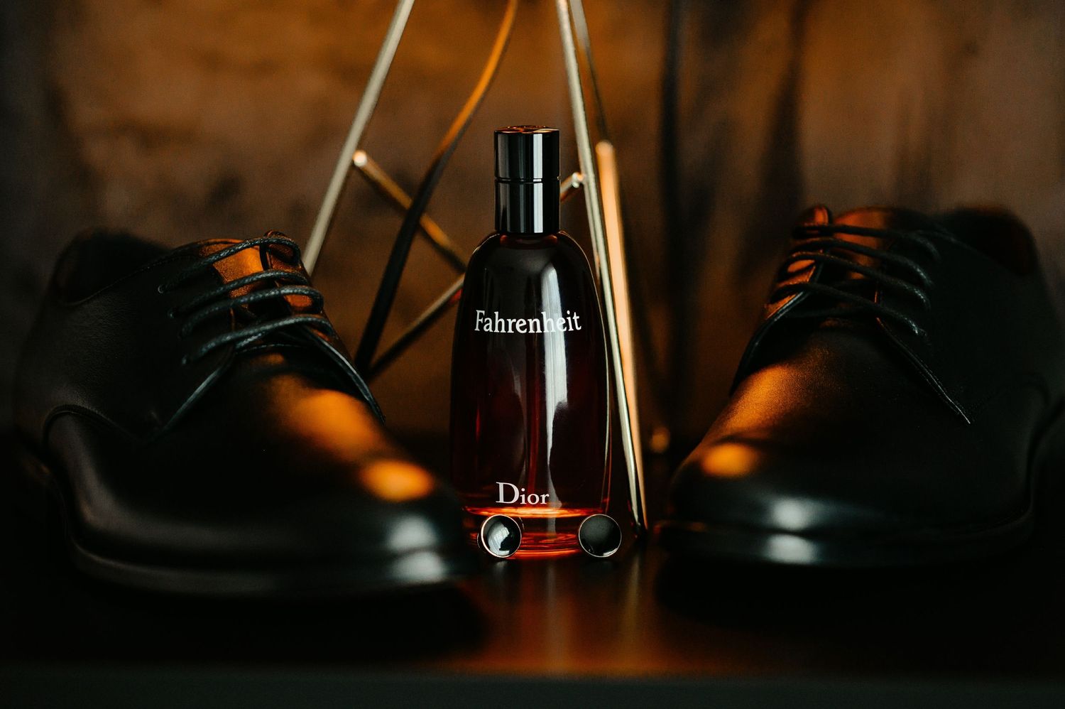 Dior Fahrenheit cologne bottle displayed between two black leather dress shoes for wedding.