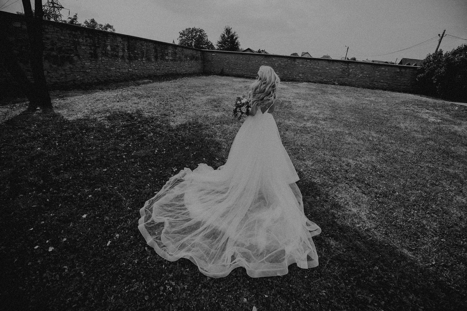 Black and white photo of bride in elegant tulle wedding gown with long train.