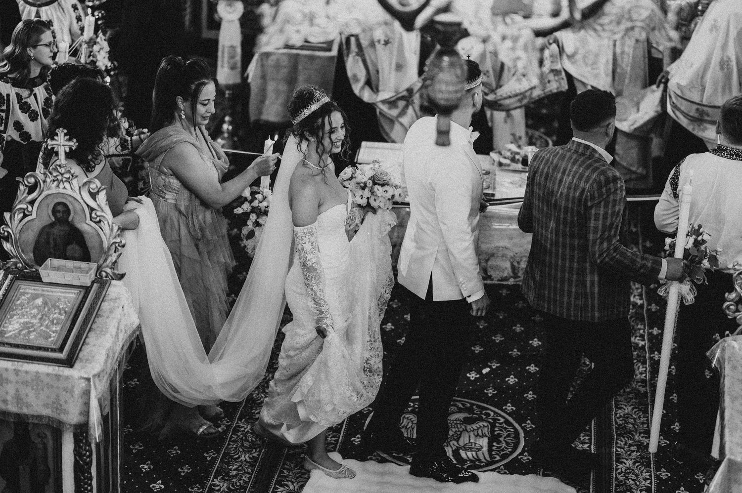 Black and white photo of a bride and groom during an Orthodox wedding ceremony inside a decorated church.