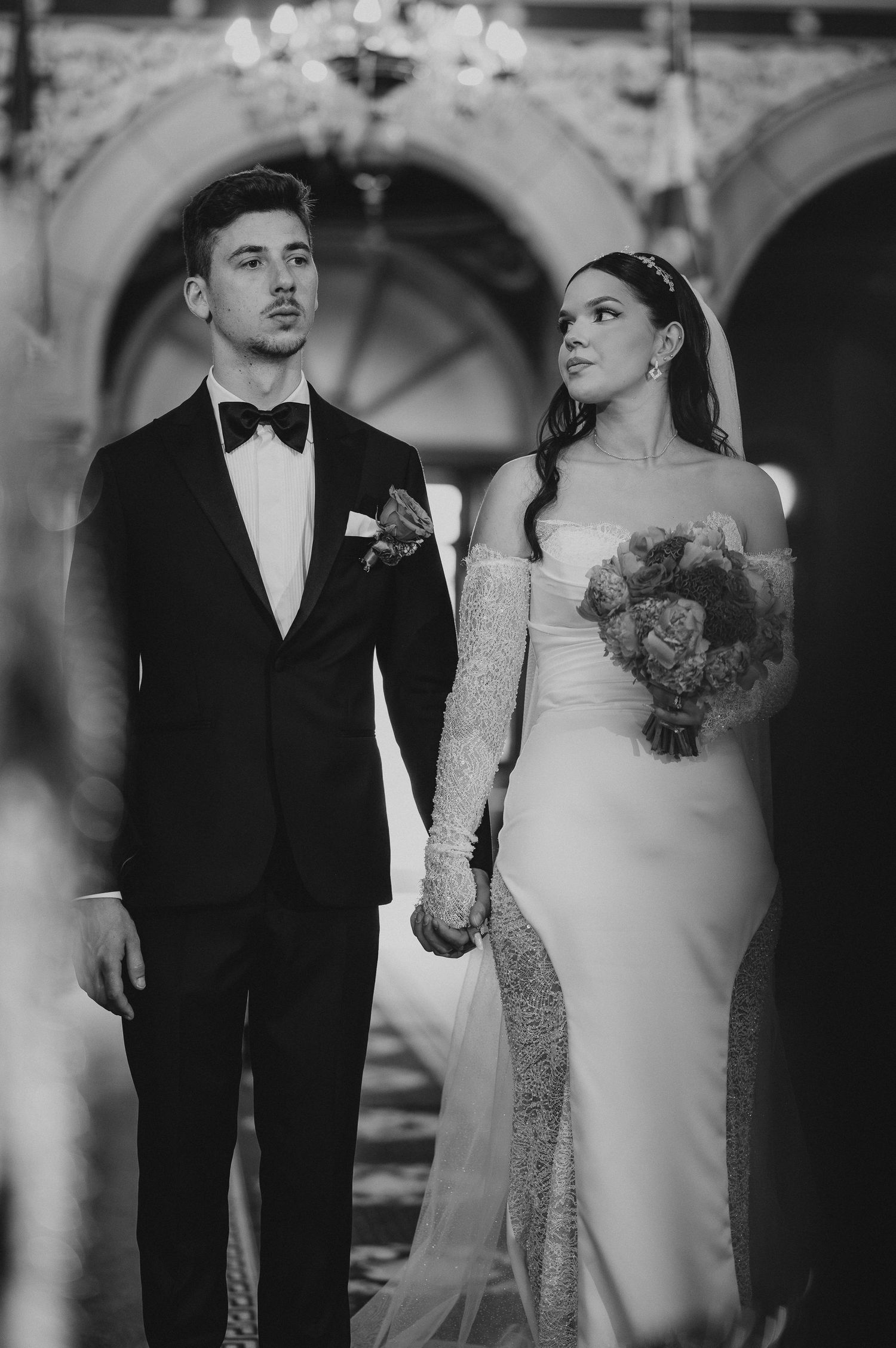 Elegant black and white portrait of bride and groom standing together during church wedding ceremony.