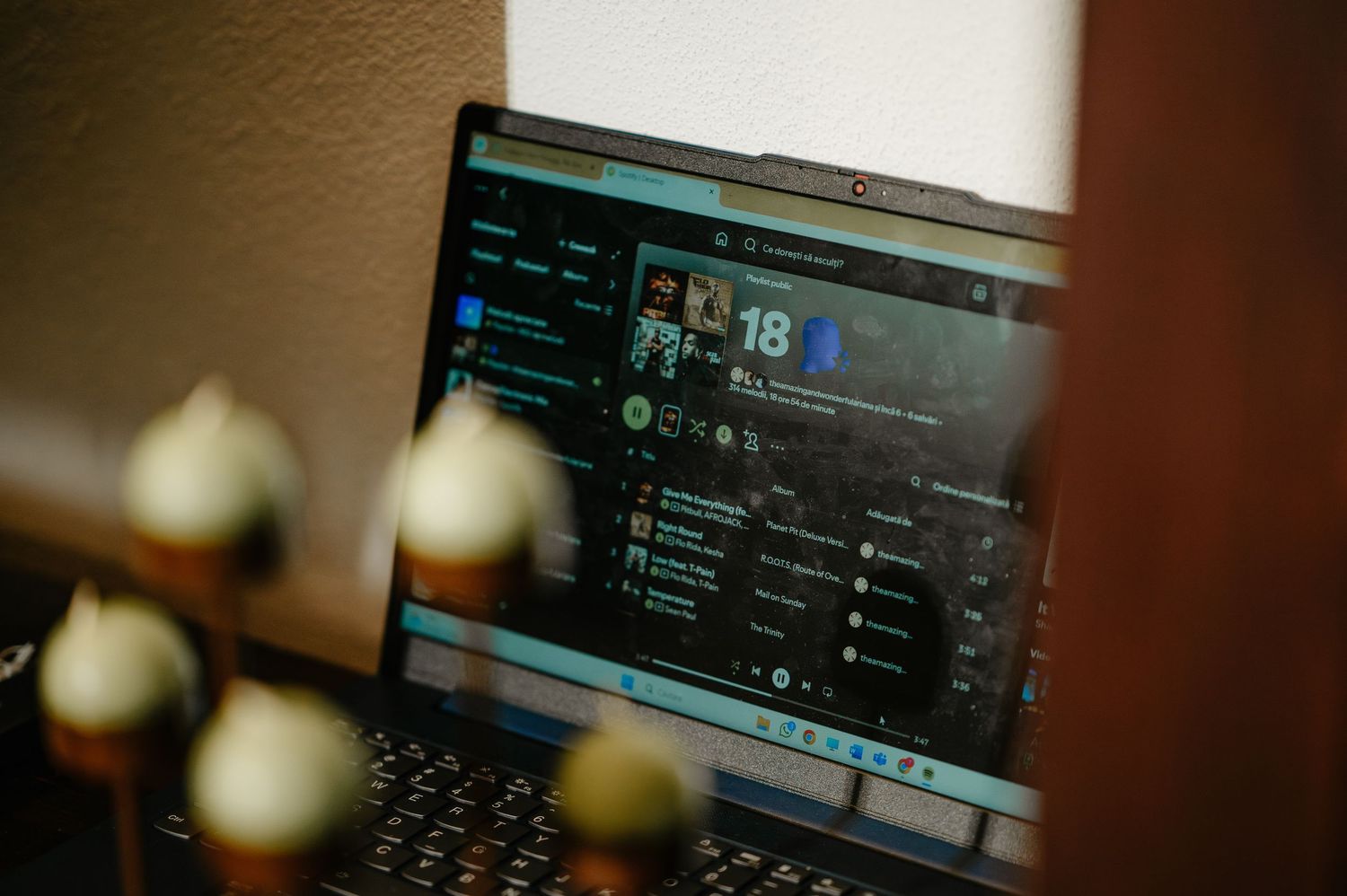 Laptop displaying a music streaming app on a dark interface with candles in the foreground.