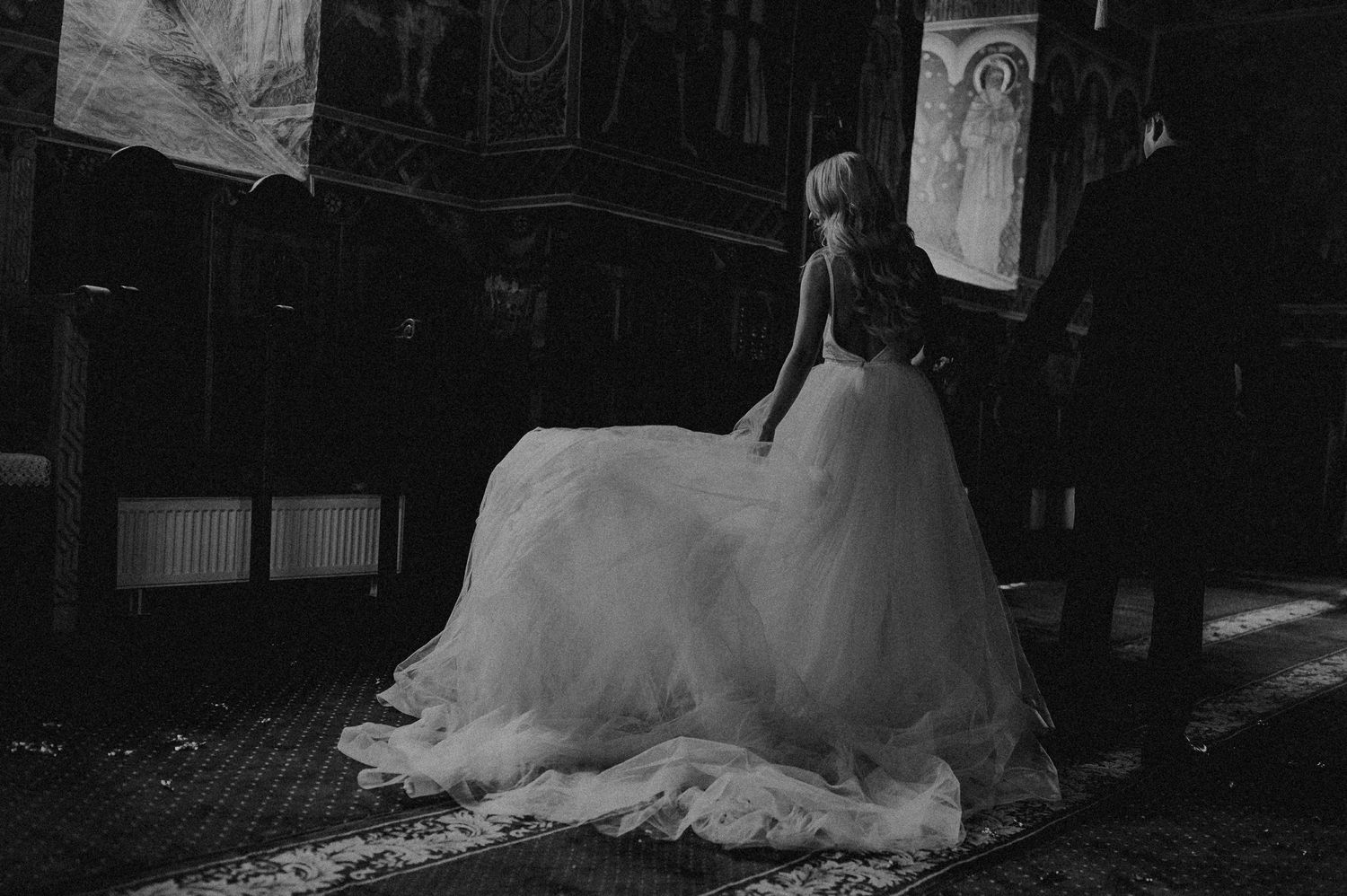 Black and white photo of bride in full tulle gown inside ornate church.