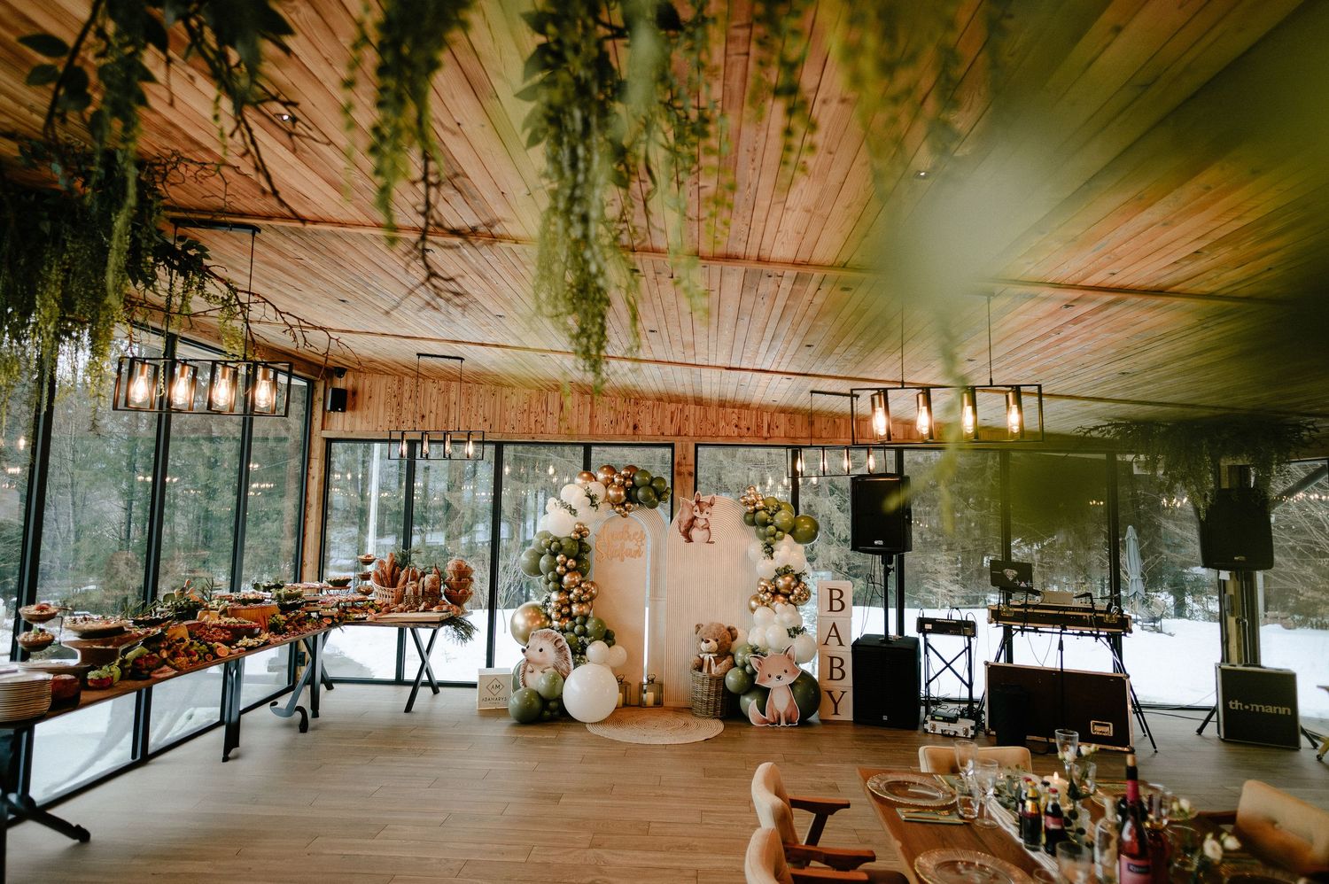Rustic chalet event venue decorated with hanging greenery, string lights, and floral arrangements in winter.