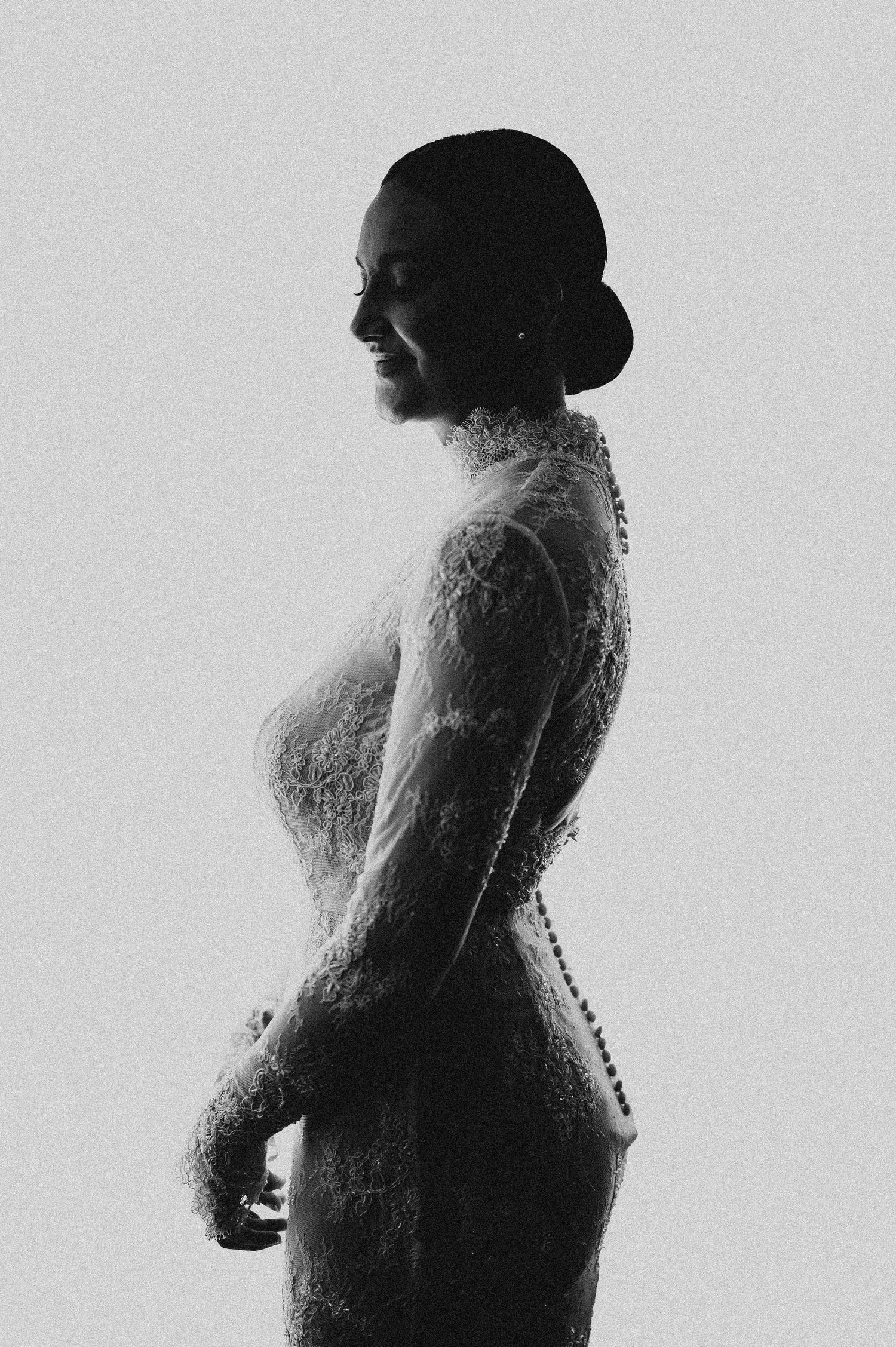 Elegant bride in long-sleeve lace wedding dress captured in a stunning black and white side profile silhouette.